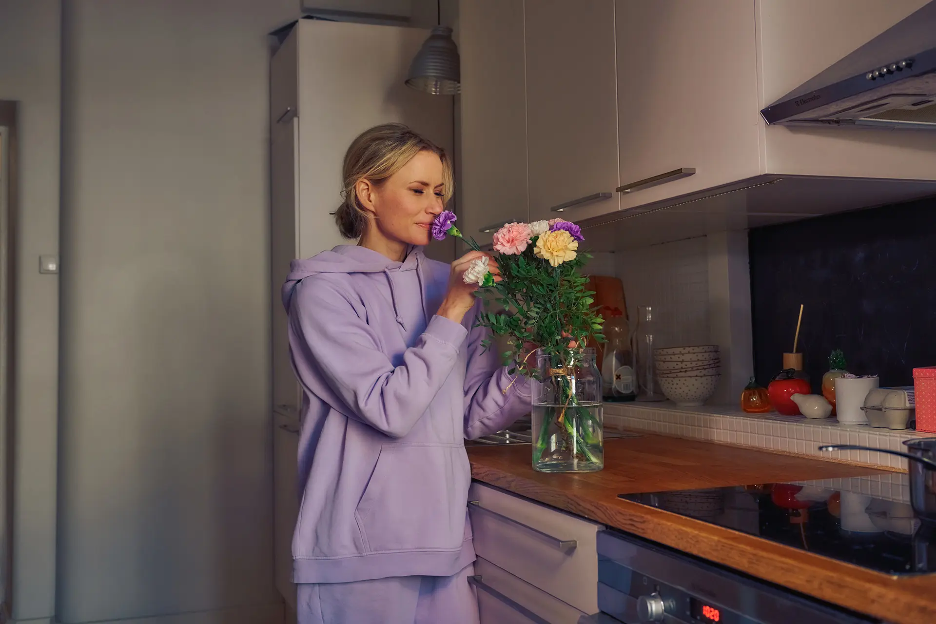 Minka Kuustonen haistaa maljakossa olevia kukkia keittiössään.