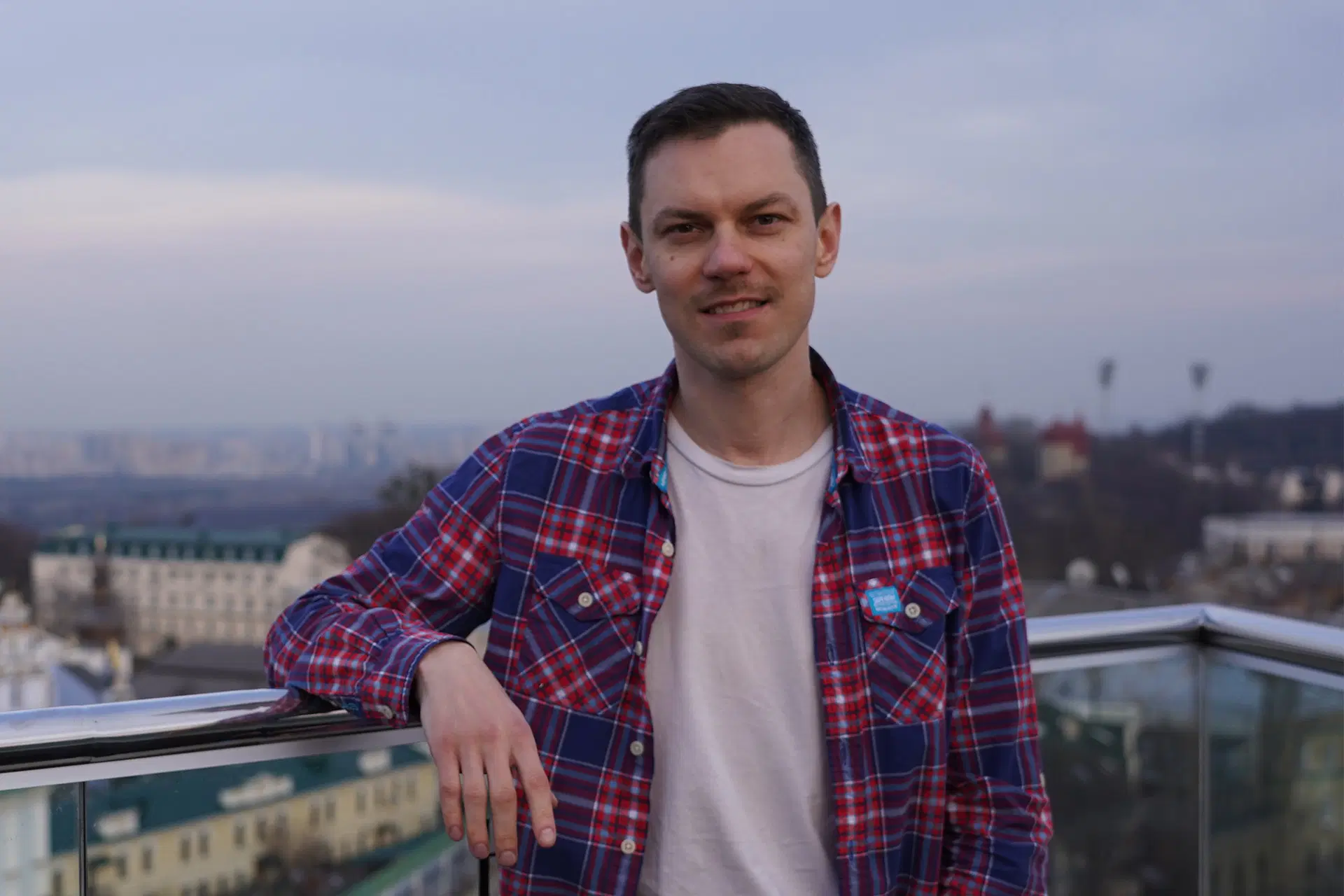 Maxin Fedorov nojaa rennosti kaiteeseen. Taustalla kaupunkimaisema.
