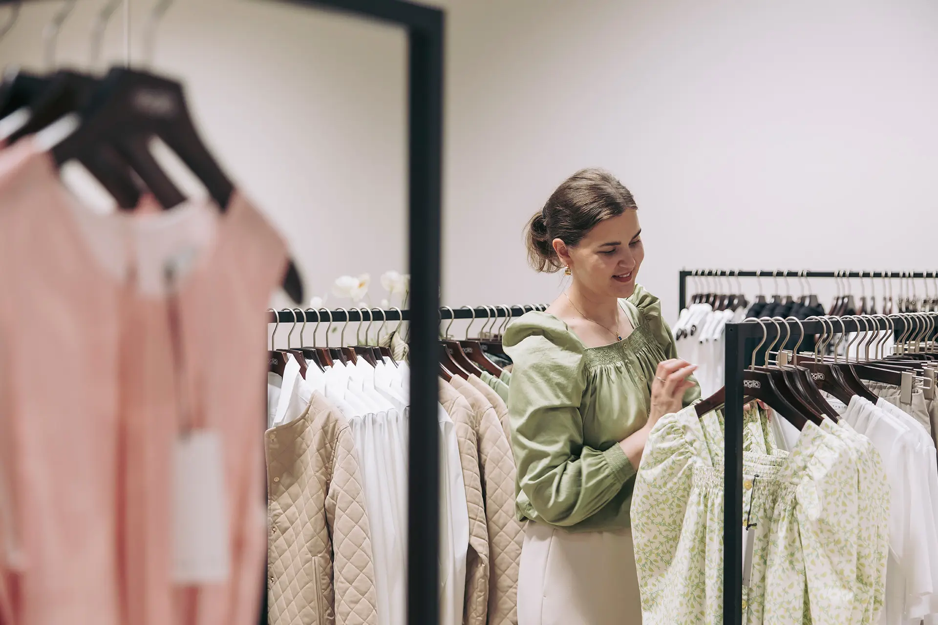 Katriina Virtanen katselee rekillä roikkuvia vaatteita.