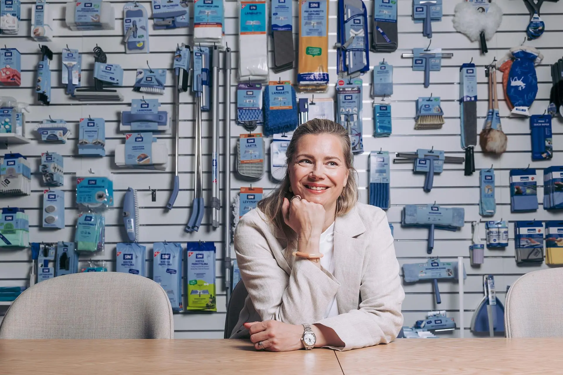 Johanna Hamro-Drotz  taustallaan paljon erilaisia Sinituotteen siivousvälineitä.