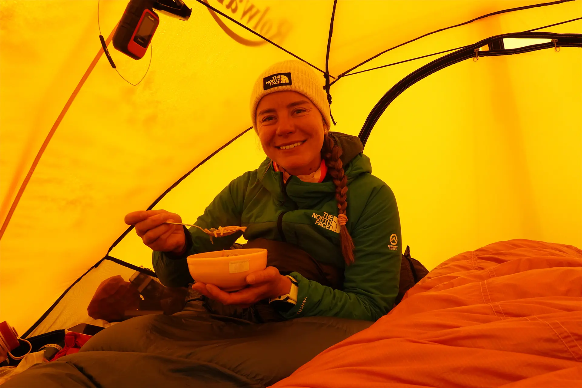 Anni Penttilä syö muovikupista ruokaa teltassa.