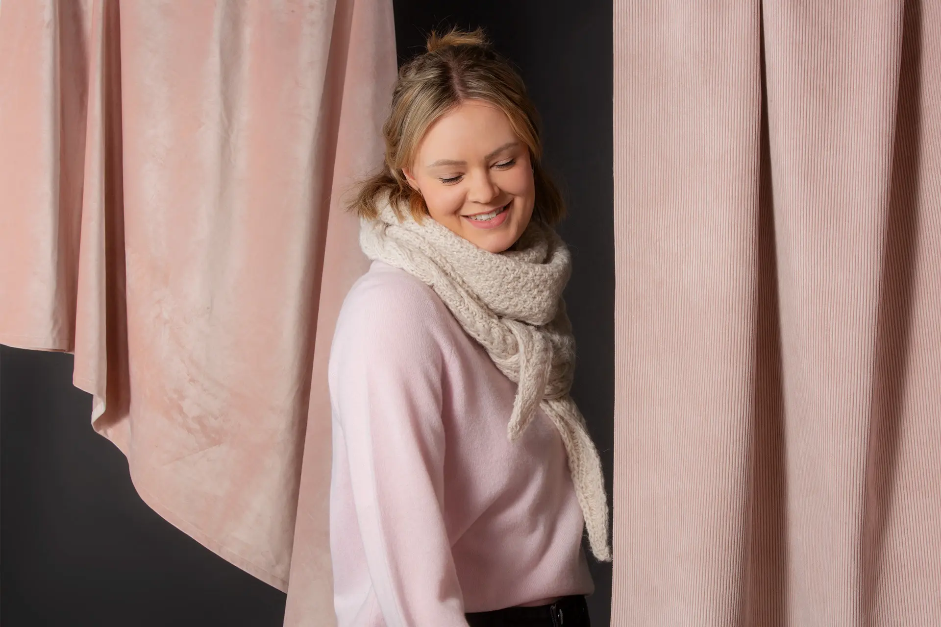 Vaaleaan neulehuiviin ja vaaleanpunaiseen paitaan pukeutunut nainen.