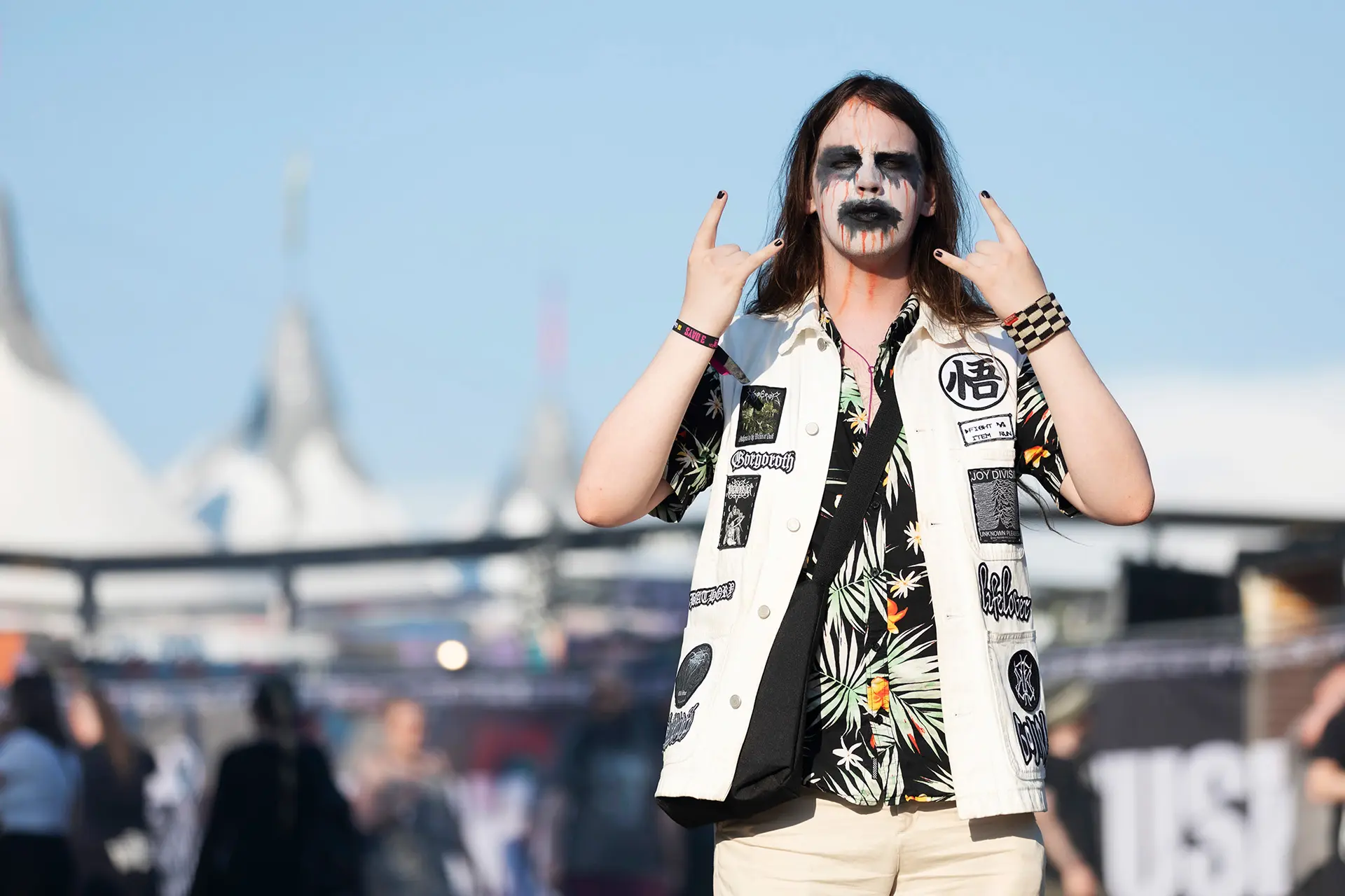 Pekka Mentunen poseeraa kasvoillaan näyttävät maalaukset ja päällään liivi, johon on ommeltu merkkejä.