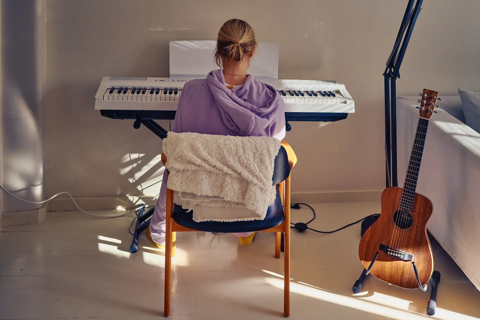 Minka Kuustonen istuu selkä kuvaajaan päin, edessä kosketinsoittimet.