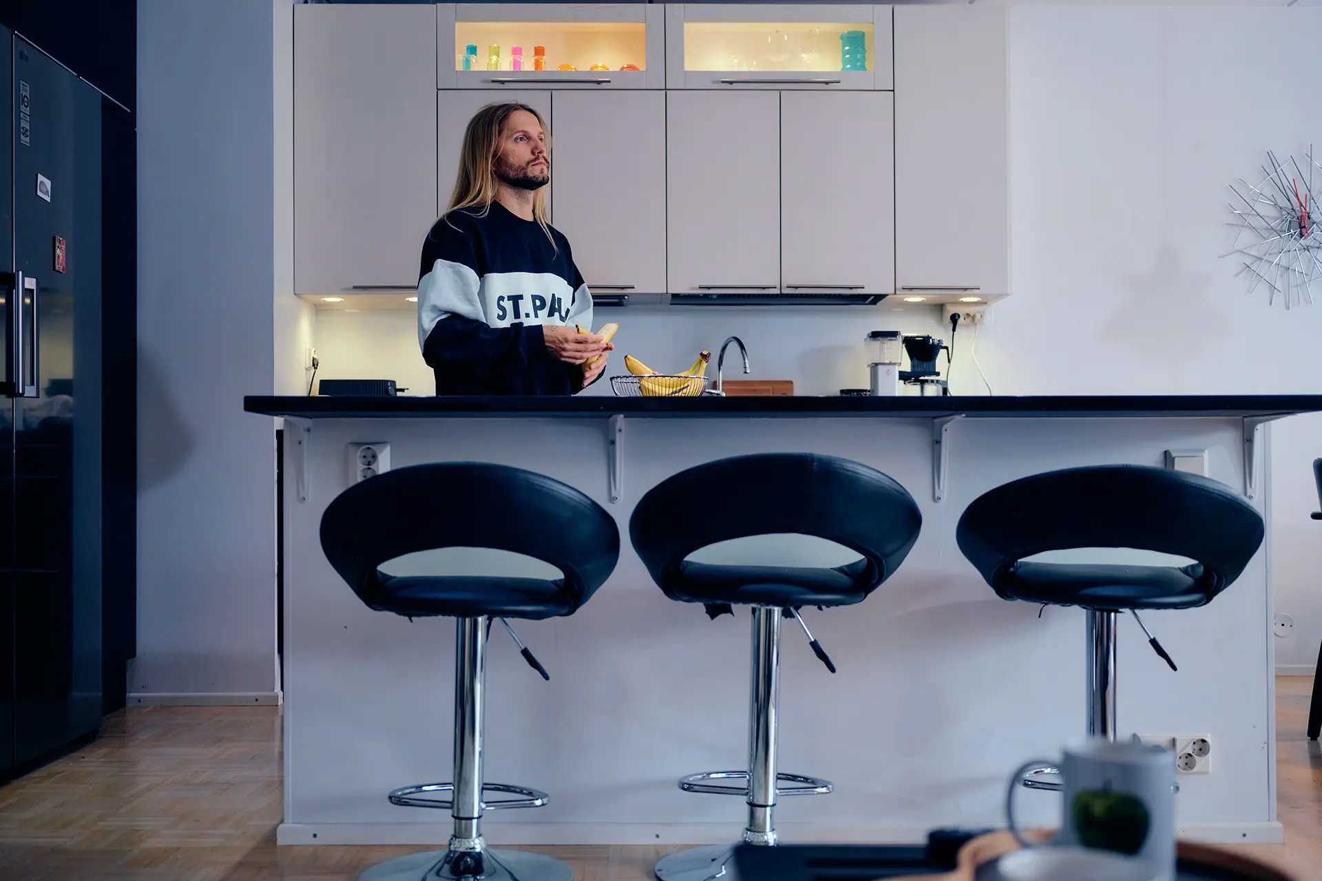 Aapo Vuori keittiössä, jossa on saareke ja korkeita tuoleja