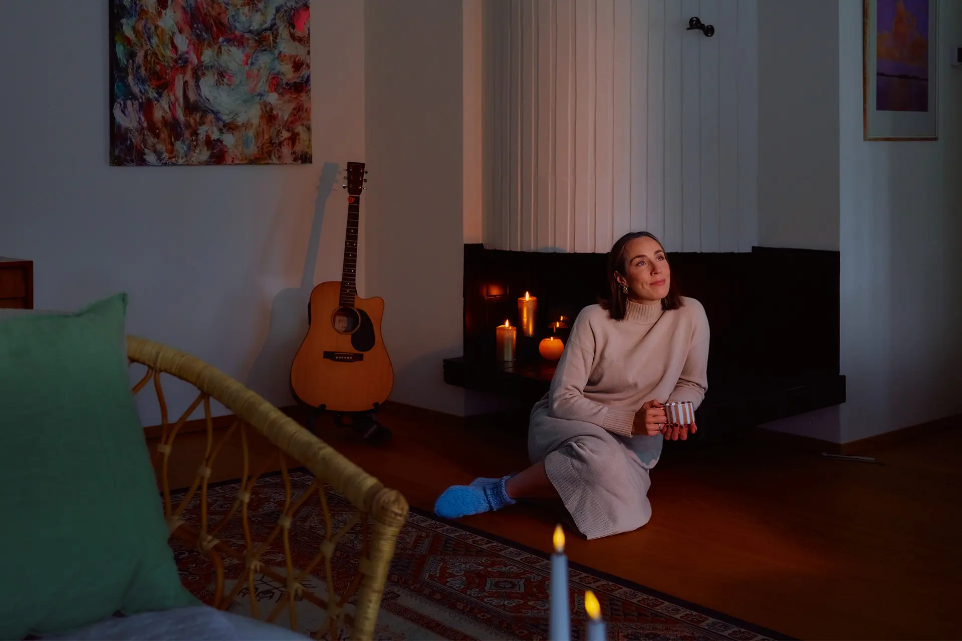 Anni Ihamäki takanaan takka, jossa palaa kynttilöitä