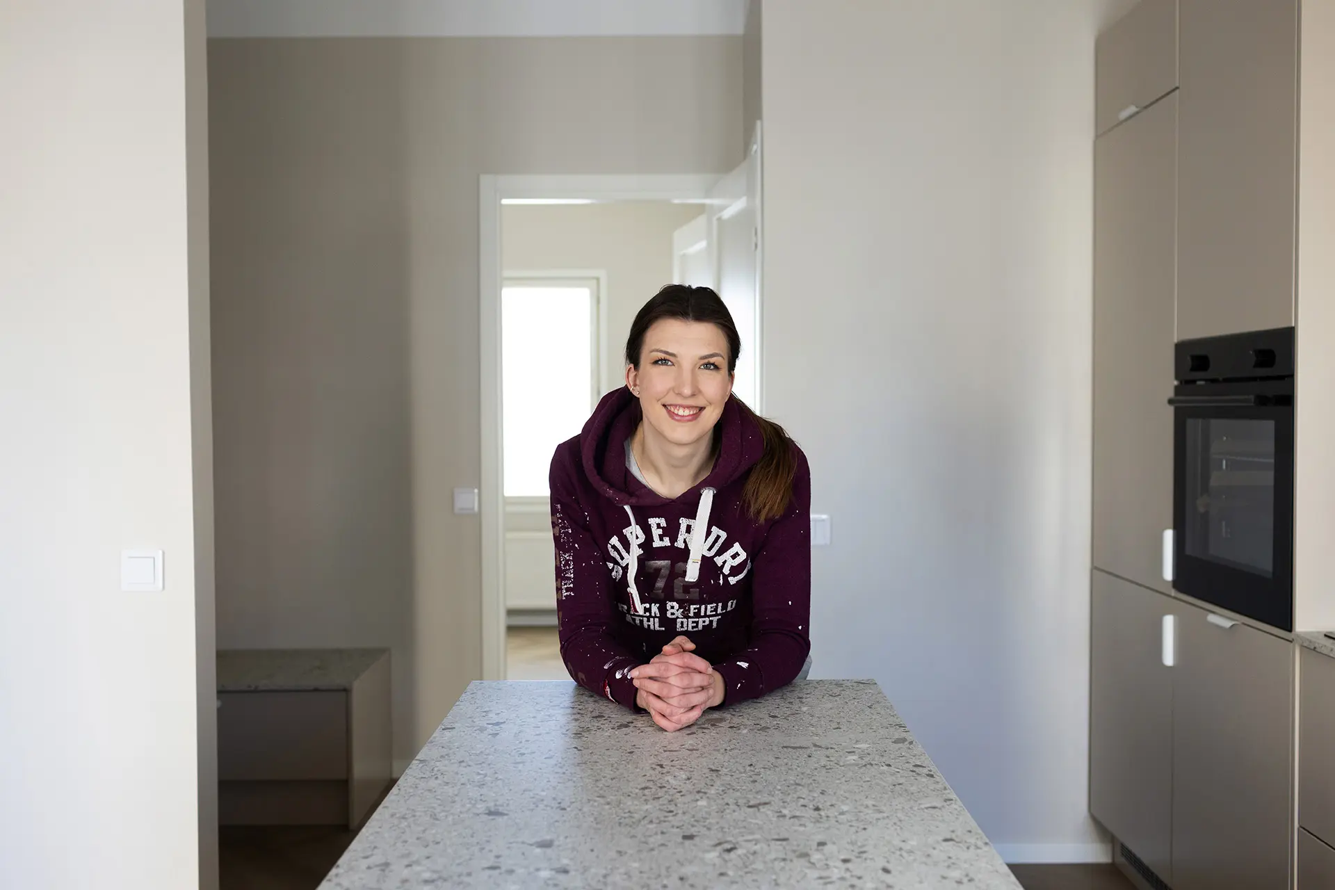 Jenniina Kuusainen nojaa saarekkeeseen keittiössä.