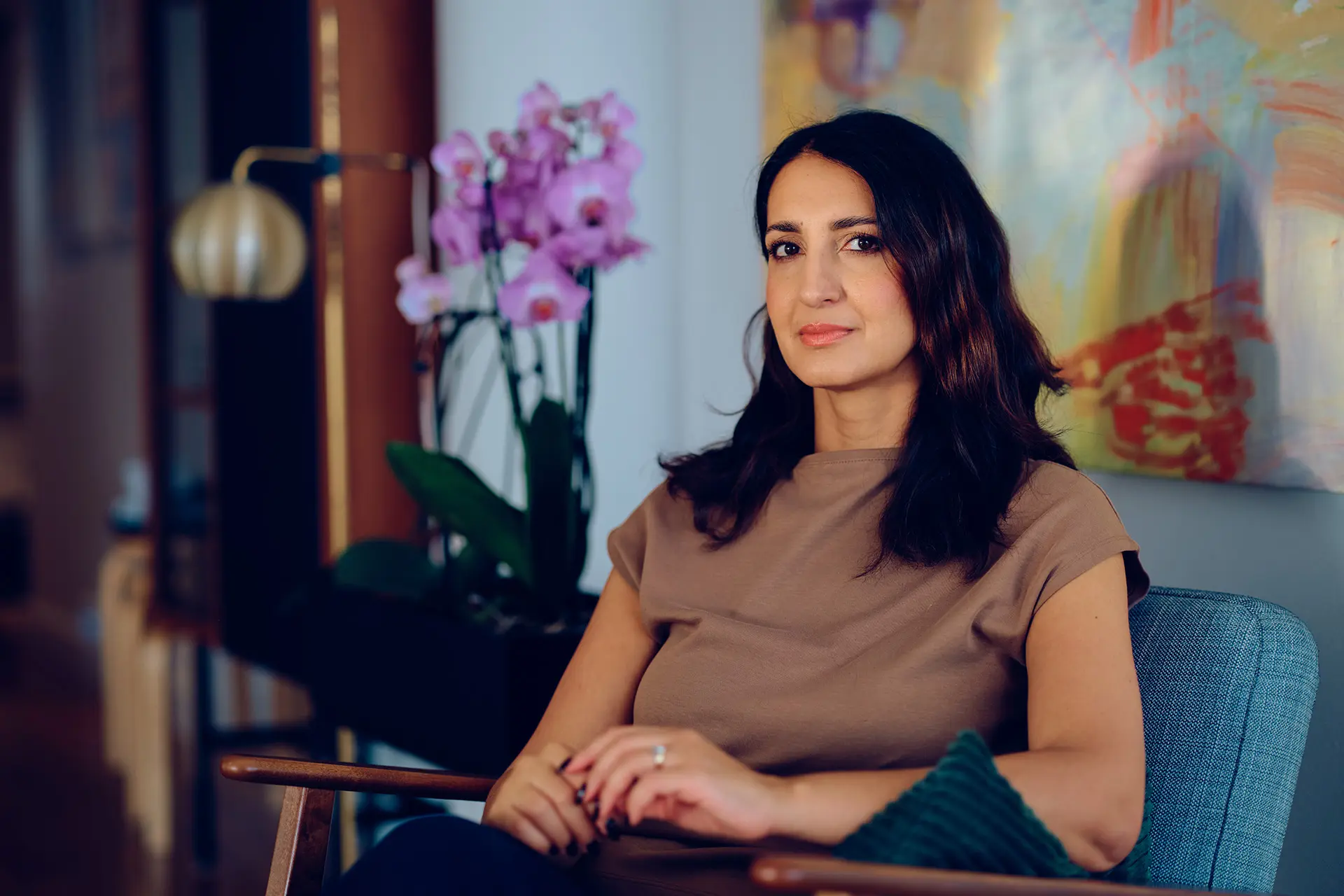 Nasima Razmyar istuu nojatuolissa, takana suuri taulu