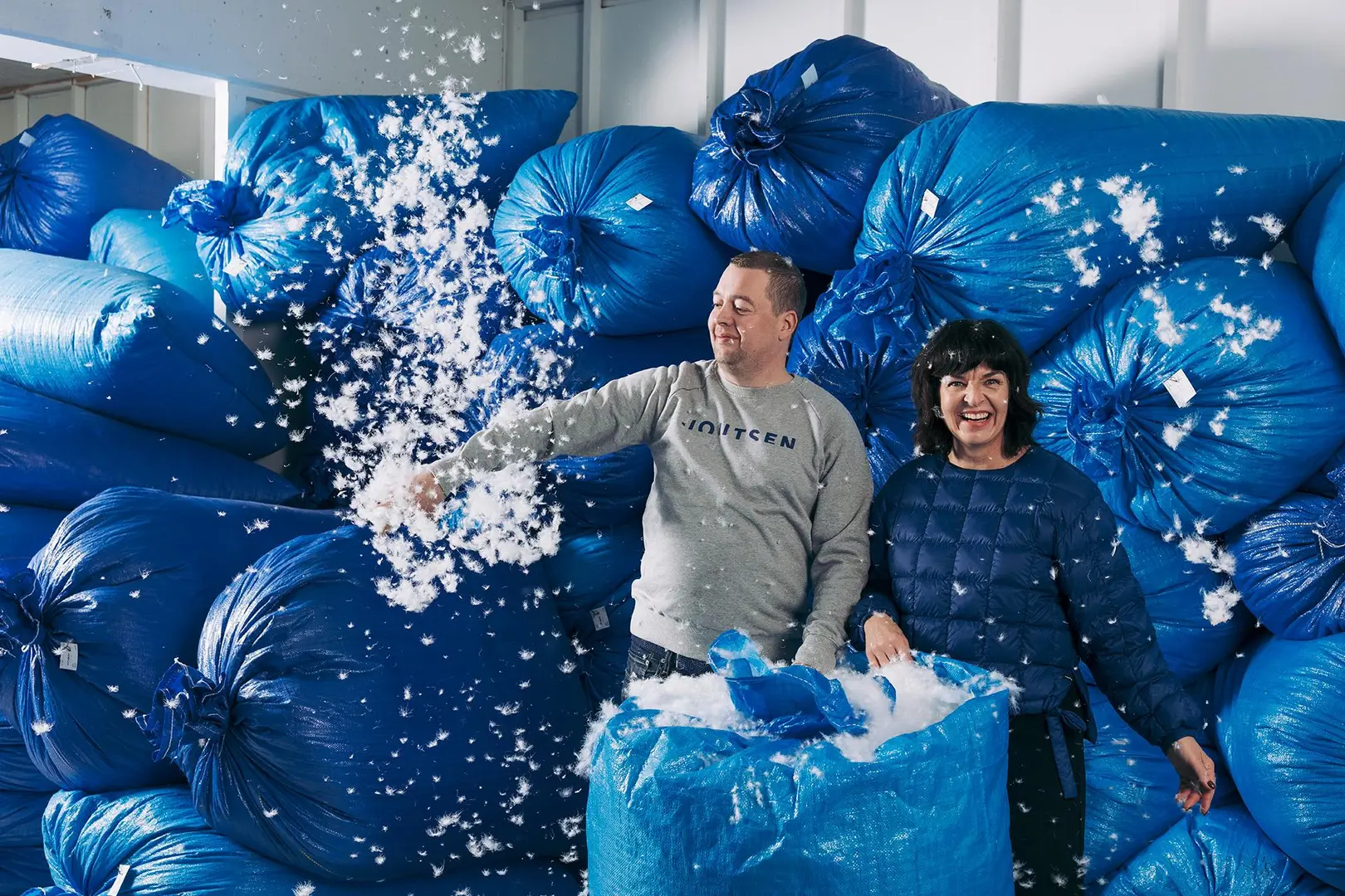 Joutsenen Matias Kotkasaari ja Katja Helén keskellä suuria säkkejä, jotka ovat täynnä untuvaa