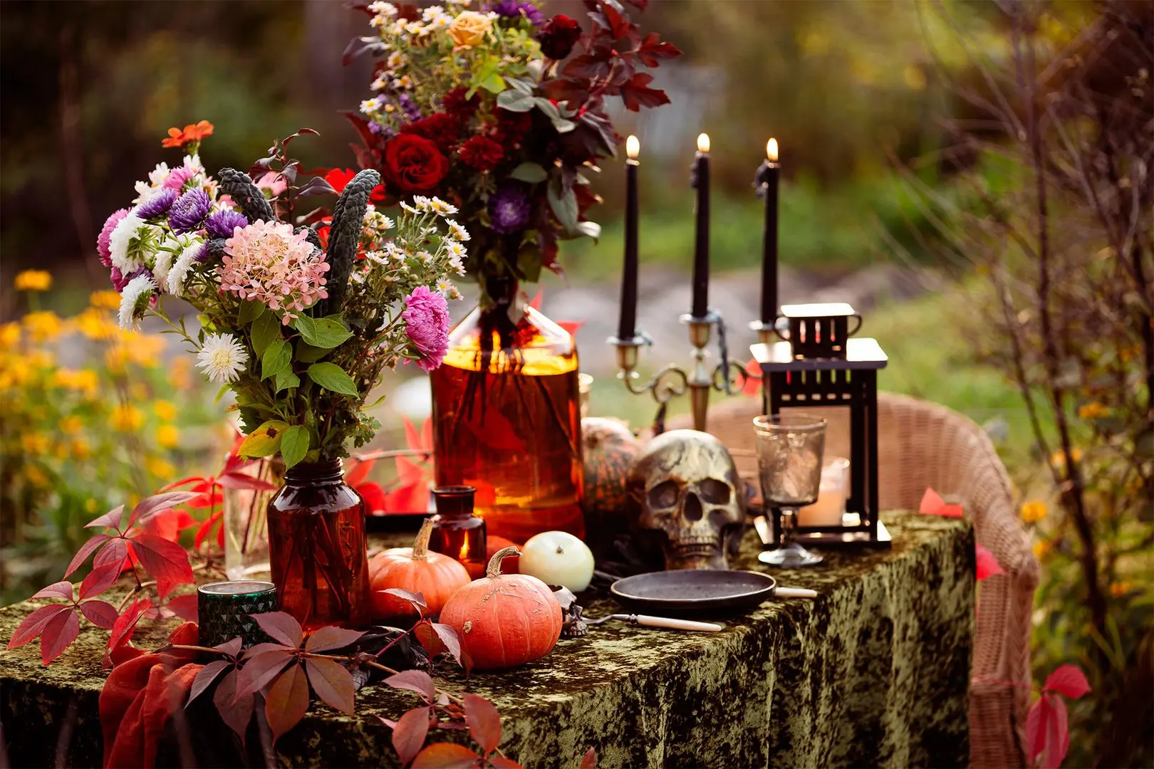 Syksyinen kattaus ulkona, pöydällä halloween-koristeita ja kynttilöitä.