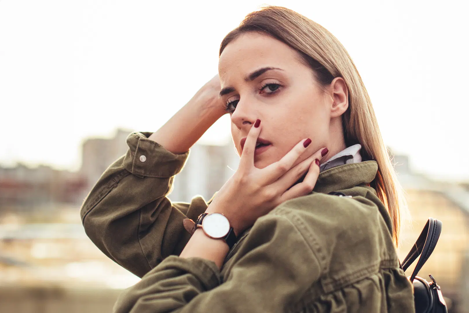 Nainen katsoo kameraan, päällä vihreä takki.