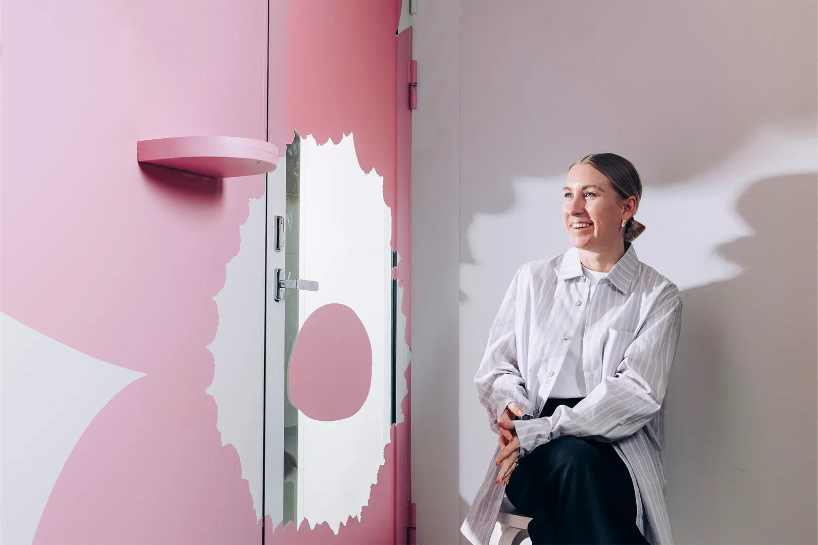 Satu Maaranen istuu tuolilla huoneessa, jonka seinään on maalattu suuri Marimekon Unikko-kuosin kukka.
