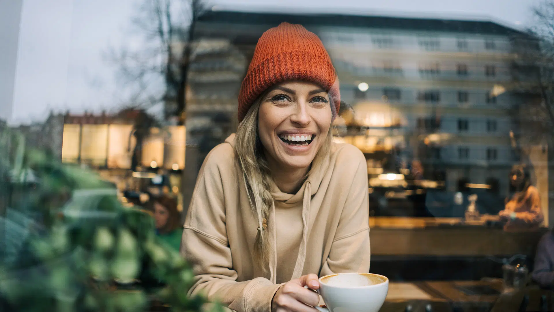 Nainen nauraa pipo päässä.