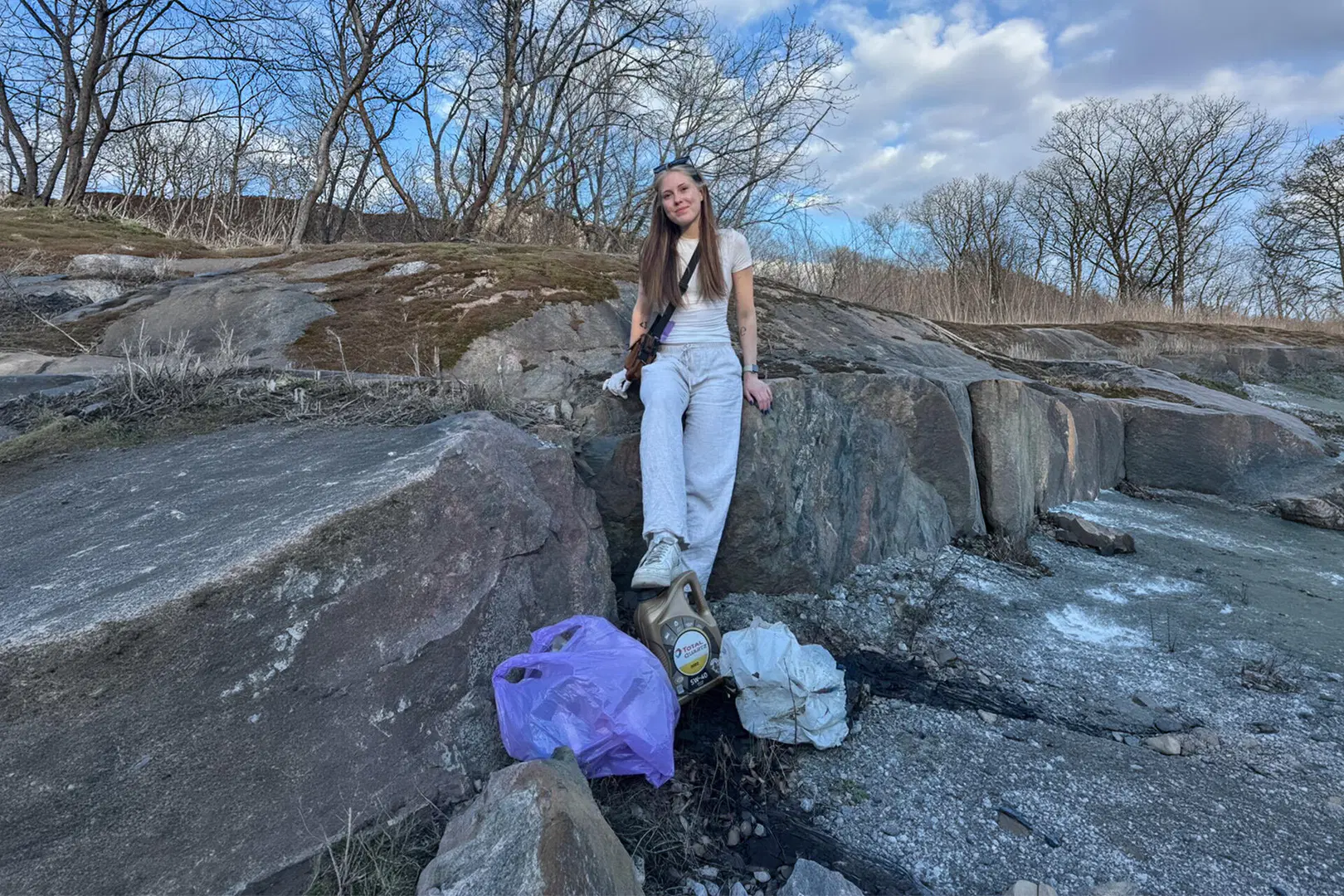 Vilma Tanner istuu kalliolla, jalkojen juuressa roskapusseja