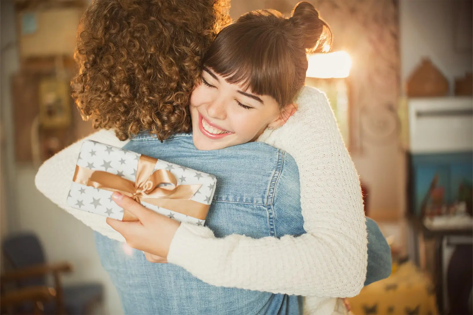 Nainen halaa paketti kädessä toista naista.