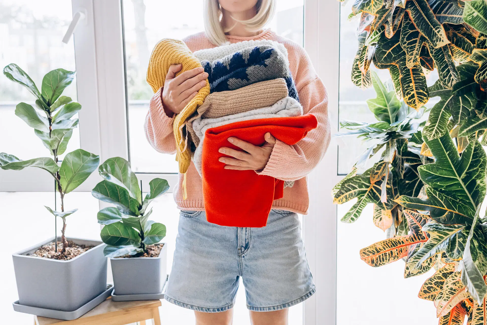 Henkilö pitää sylissään kirkkaan värisiä villapaitoja.