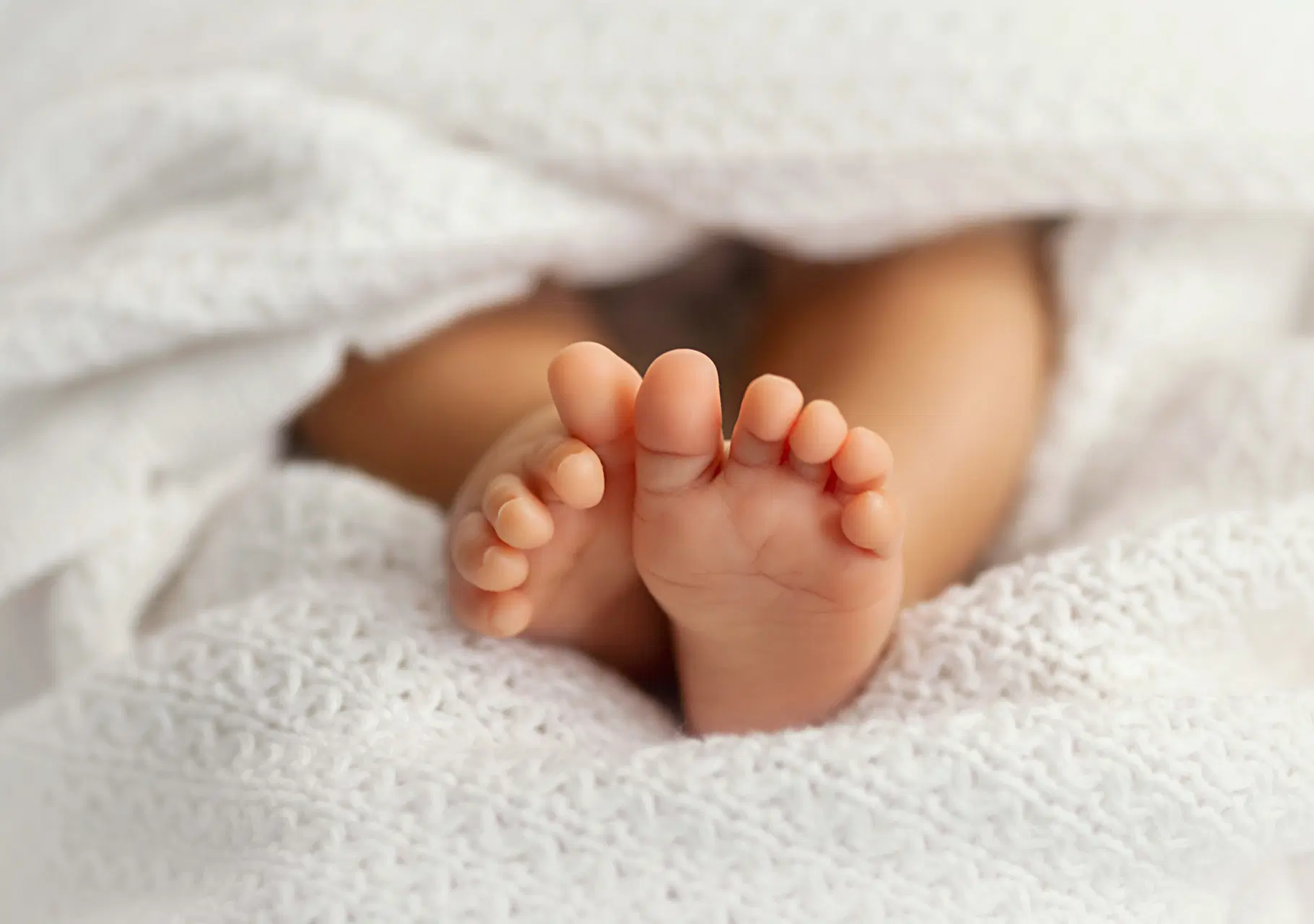 Vauvan jalat valkoisen peitteen päällä