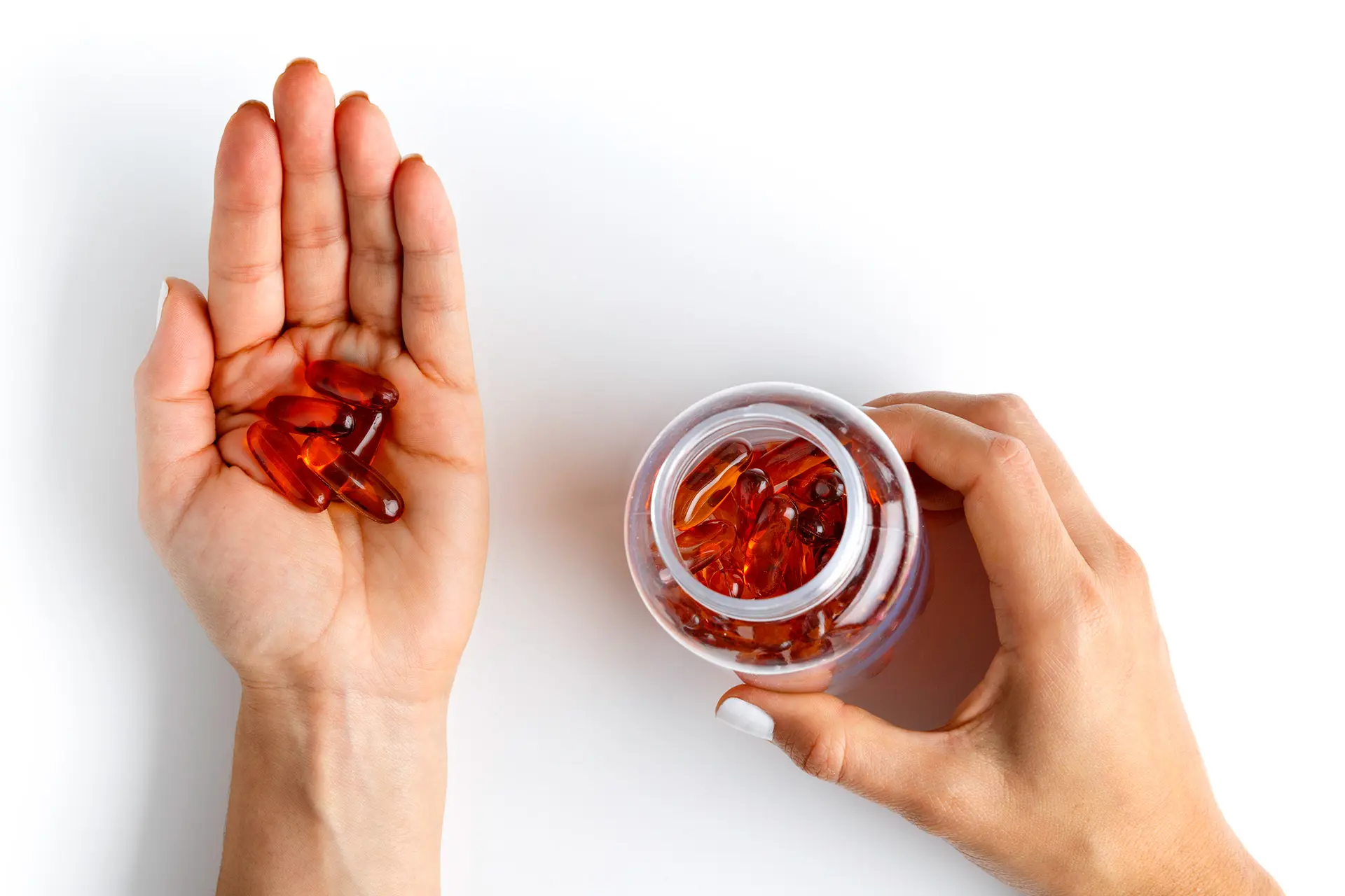 Kädelle on kaadettu punaisia pillereitä, toinen käsi pitelee pilleripurkkia.