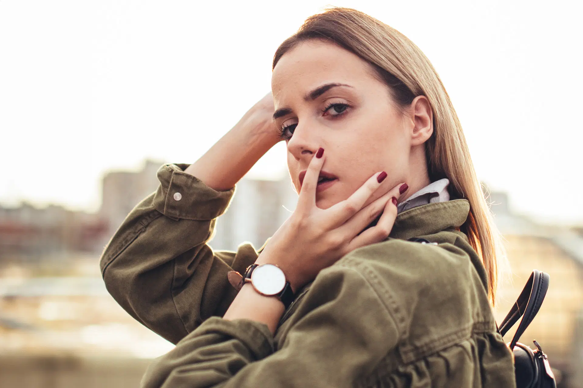 Nainen katsoo kameraan, päällä vihreä takki.