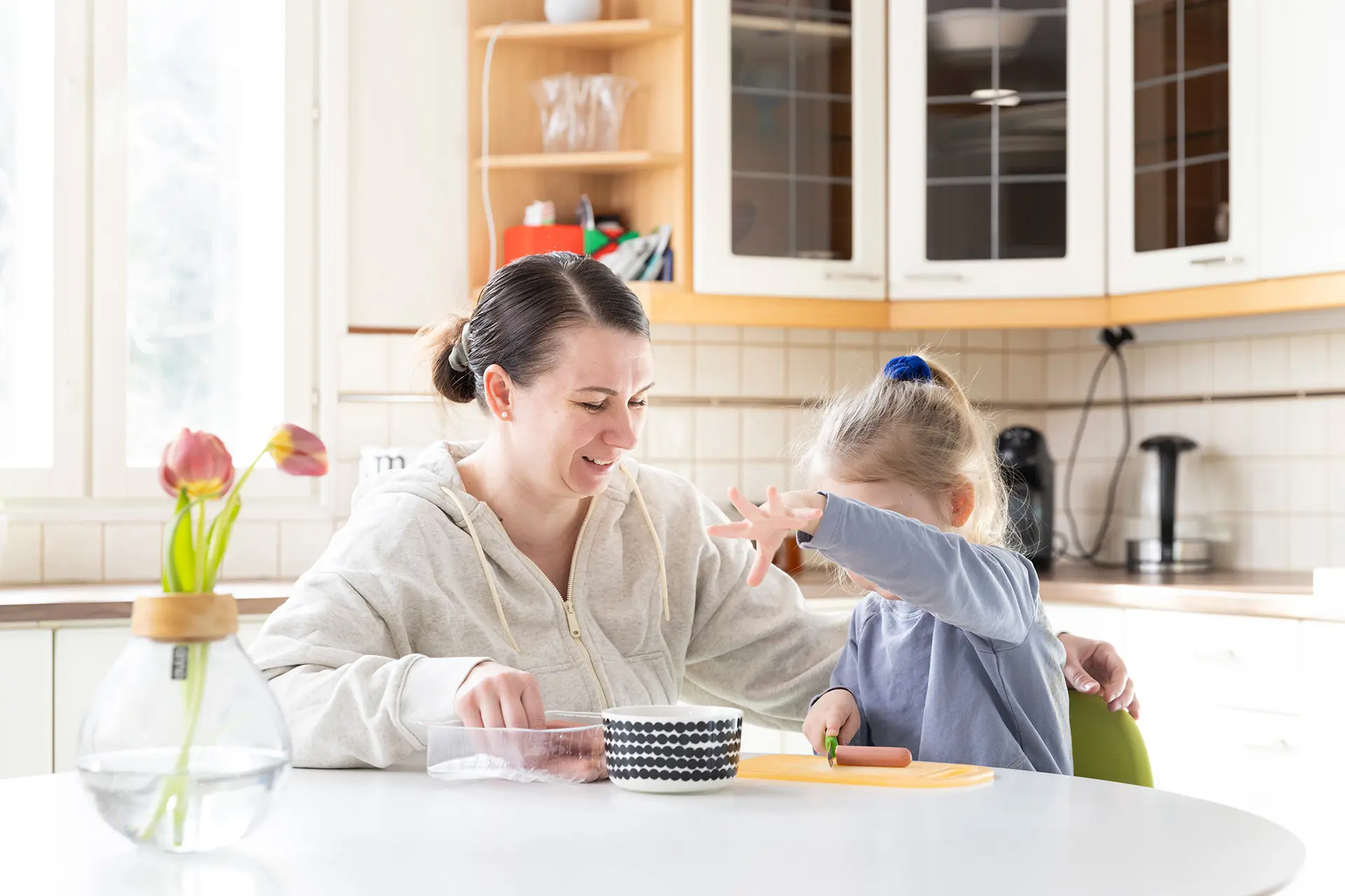 Henni Malmberg tyttärensä kanssa keittiönpöydän ääressä.
