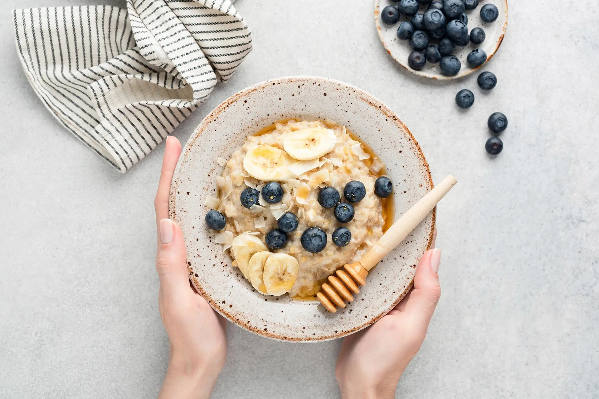 Lautasellinen kaurapuuroa, jonka päällä on banaaniasiivuja, mustikoita ja hunajaa.