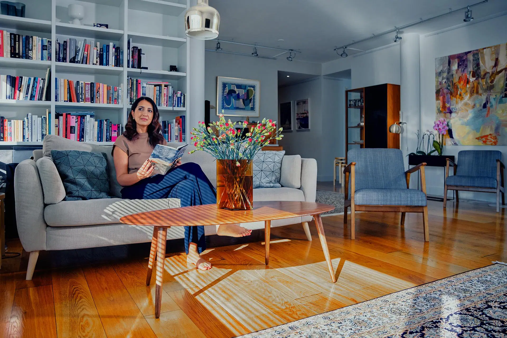 Nasima Razmyar olohuoneensa sohvalla lukemassa aikakauslehteä
