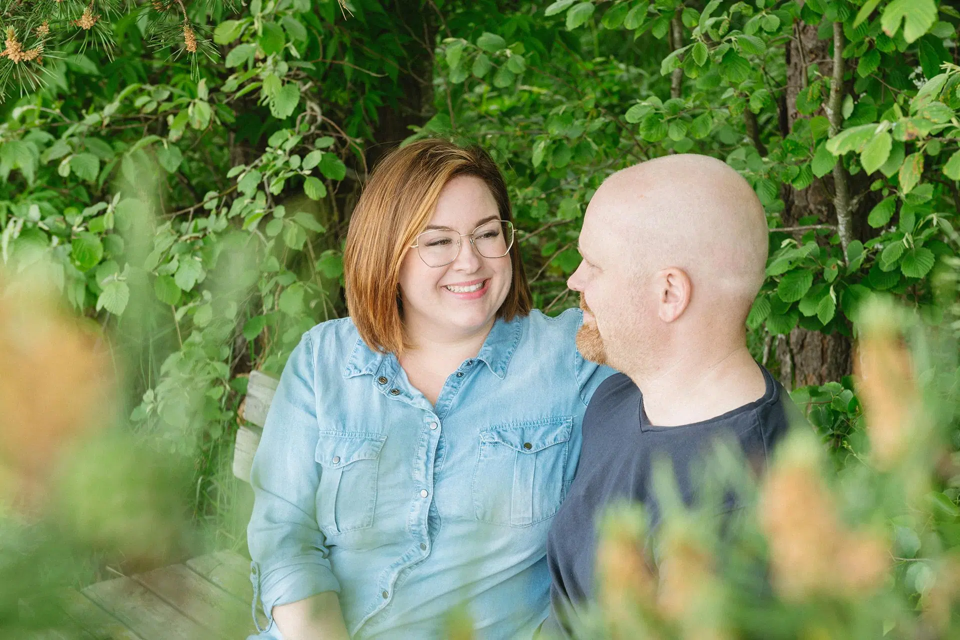 Nainen ja mies katsovat toisiaan hymyillen, taustalla puita.