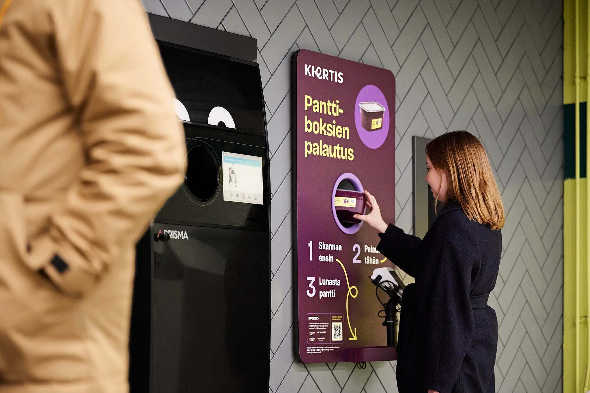 Nainen palauttaa käytetyn noutoruokarasian palautuspisteeseen.