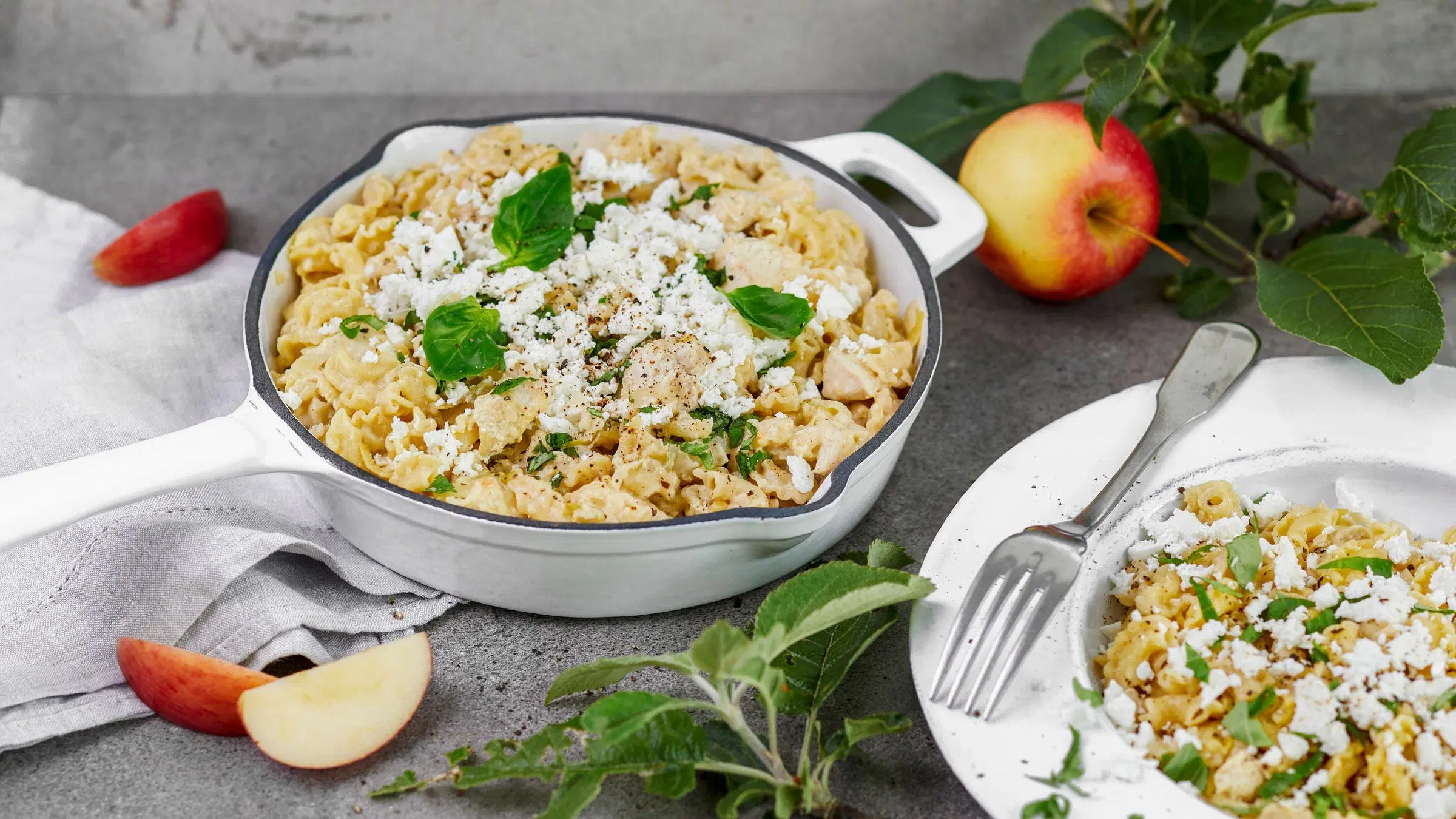 Kana-omenapasta pannulla, koristeltu salaattijuustolla ja basilikalla