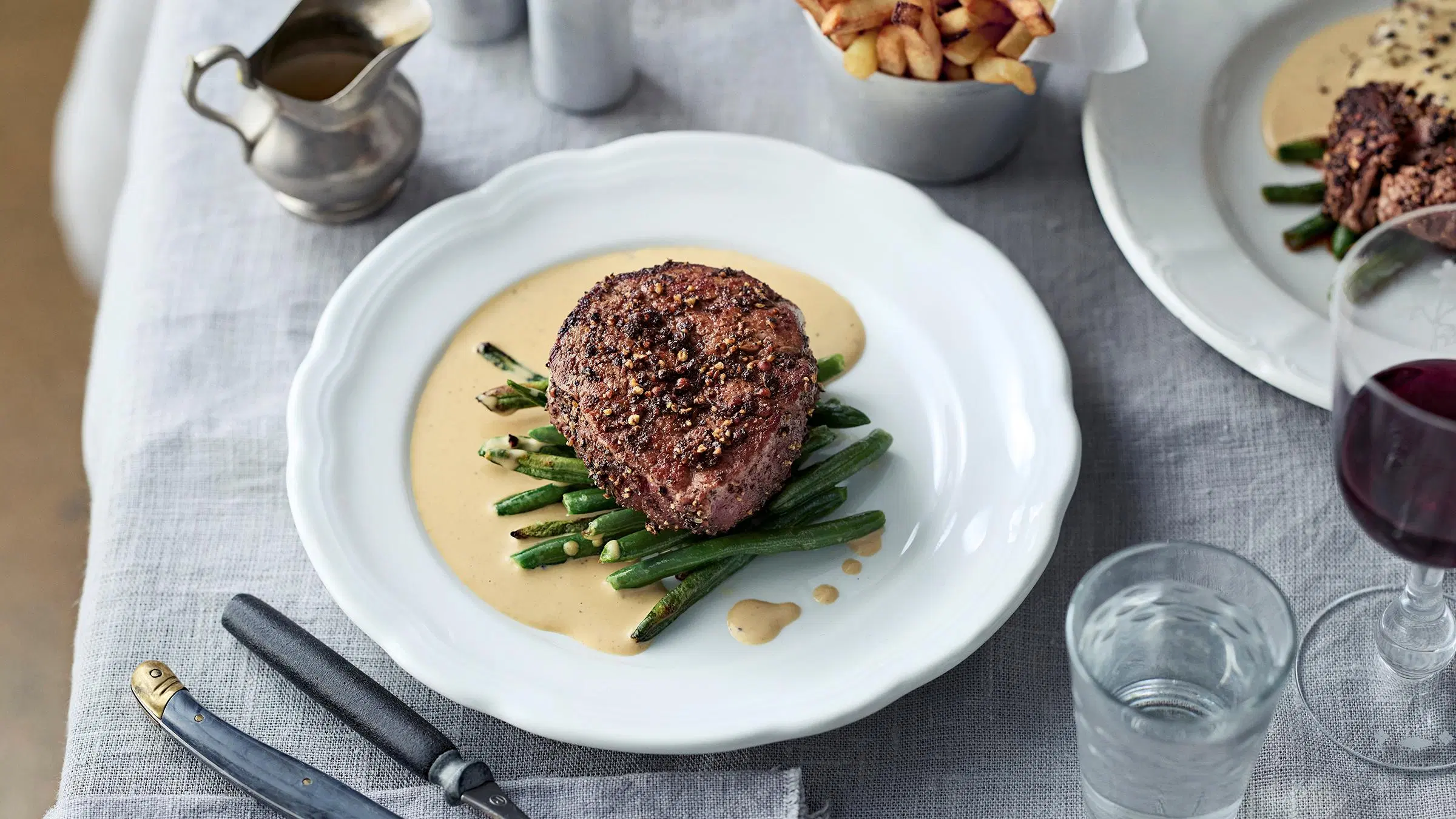 Pippuripihvi, kermakastiketta ja vihreitä papuja lautasella.