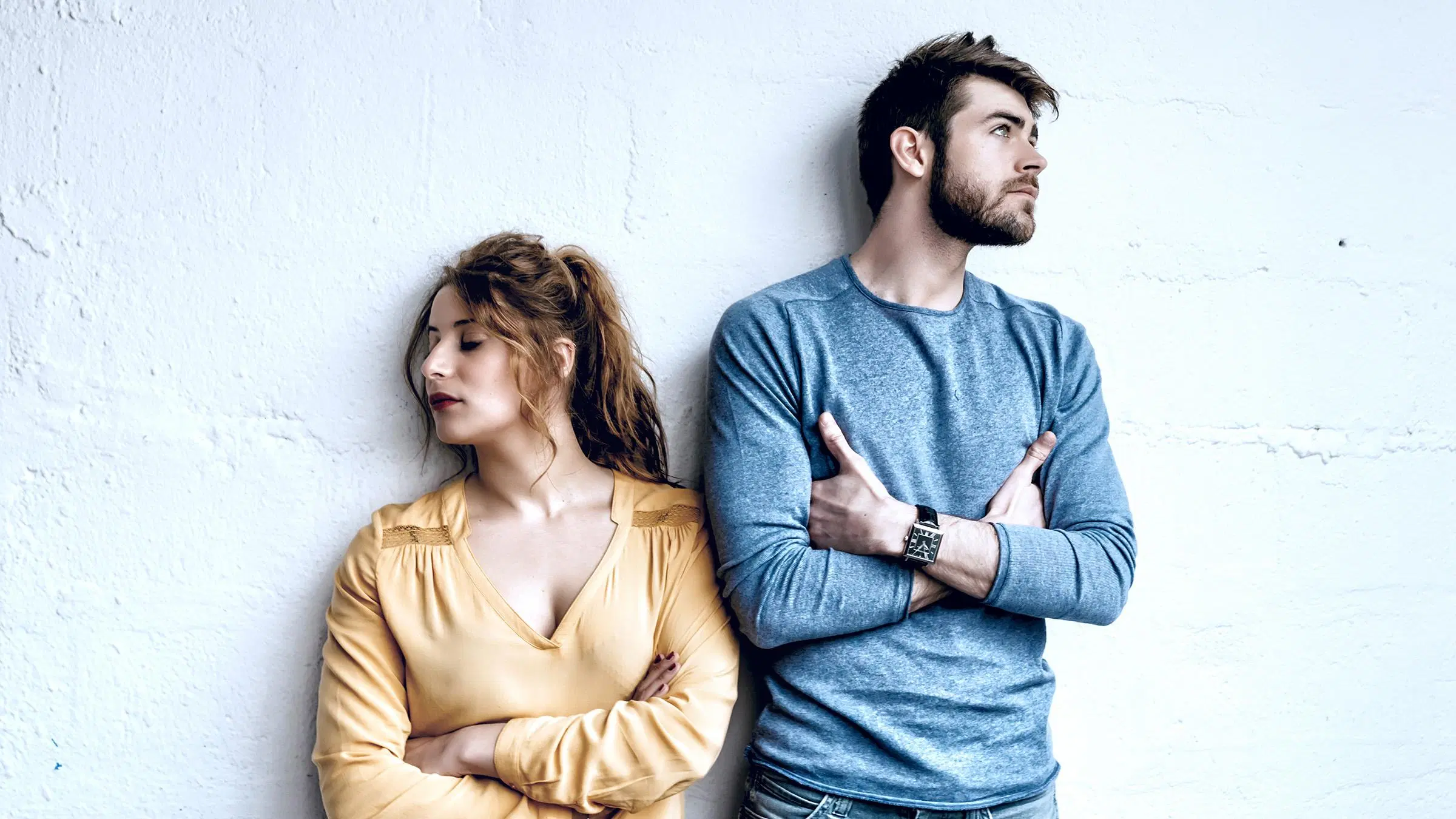 Riidoissa olevan näköinen pariskunta, nainen katsoo vasemmalle ja mies oikealle, molemmilla kädet puuskassa.