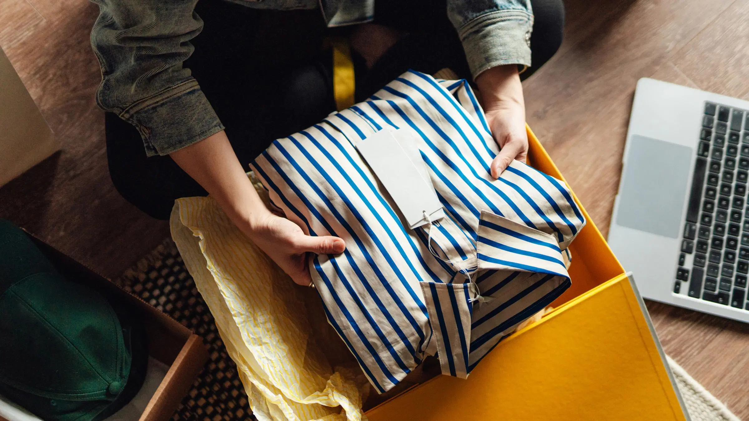 Ihmisen kädet nostavat paketista raidallisen paidan