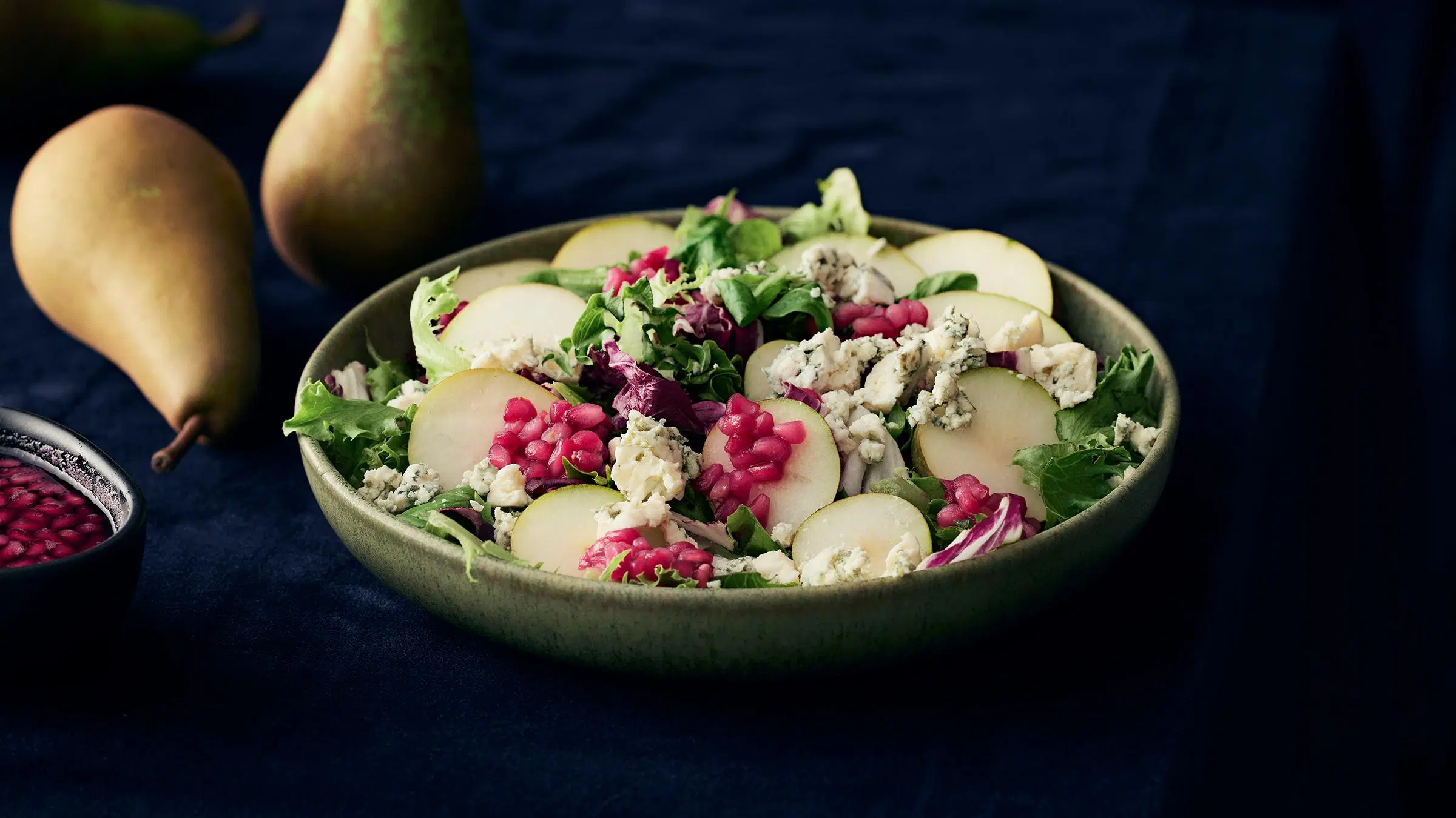 Päärynä-juustosalaattia vihreässä kulhossa.