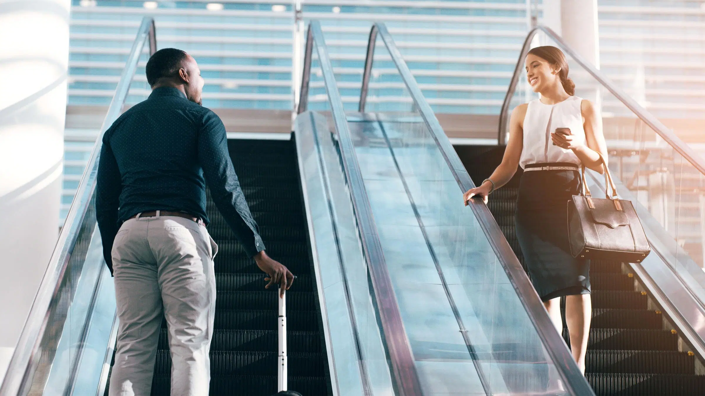 Mies ja nainen katsovat toisiaan liukuportaissa.