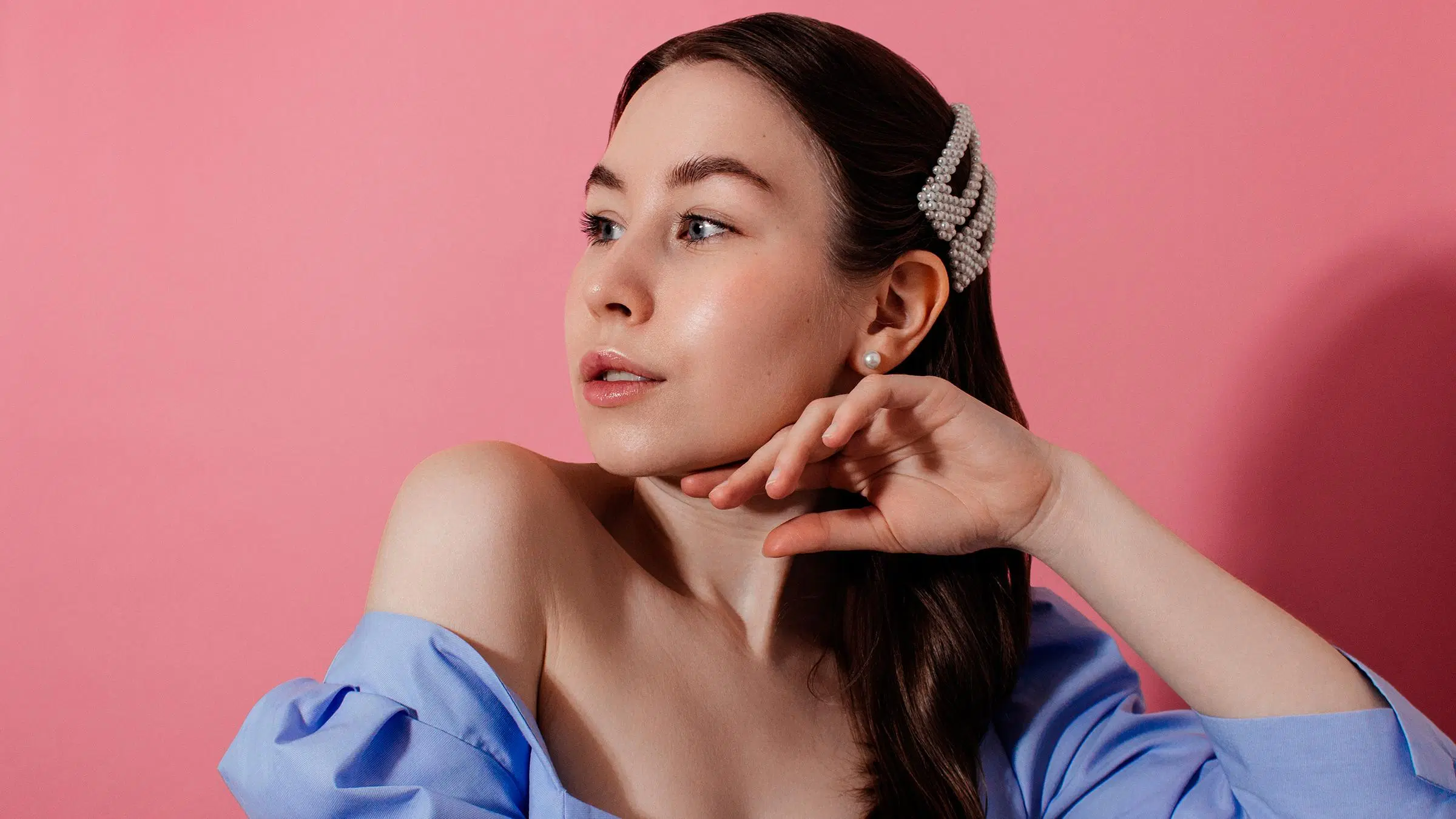 Nainen, jolla on kaksi helmikoristeista hiuspinniä tummissa hiuksissa.