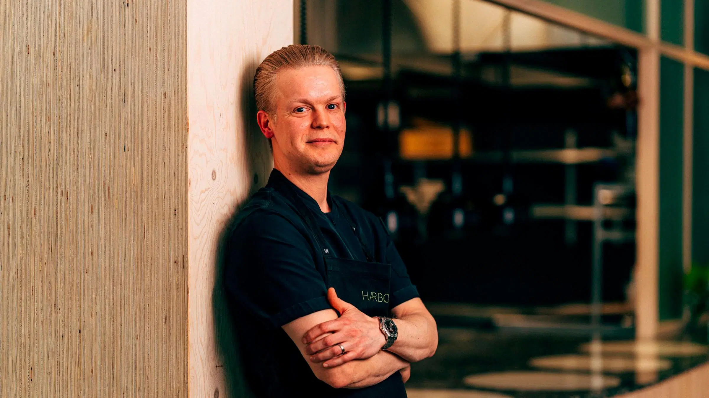 Viljami Broas nojaa rakennuksen puiseen seinään.