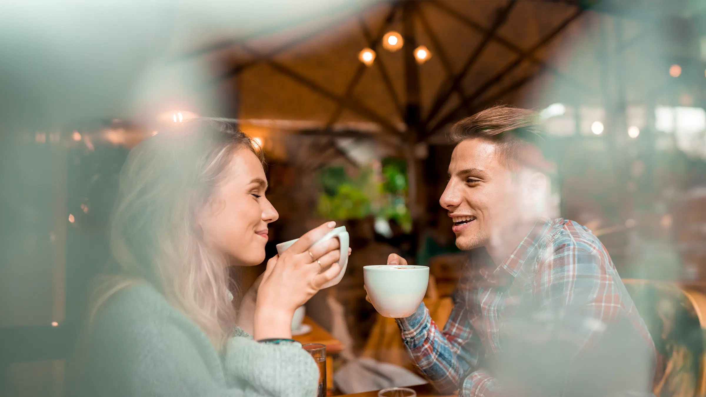 Pariskunta istuu kahvikupin ääressä ja katsoo toisiaan.