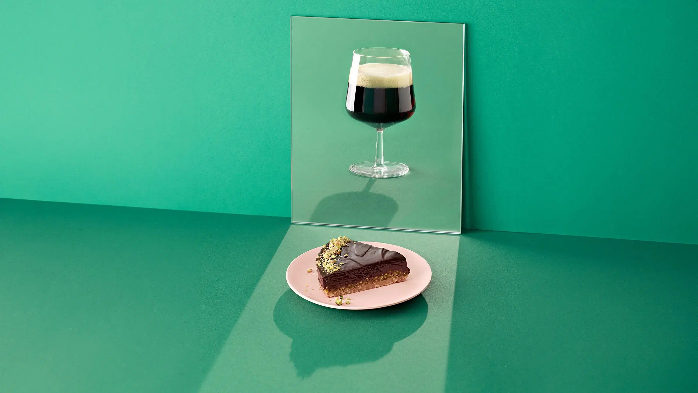 Lasi porter-olutta sekä lautasella pala suklaapistaasitorttua.