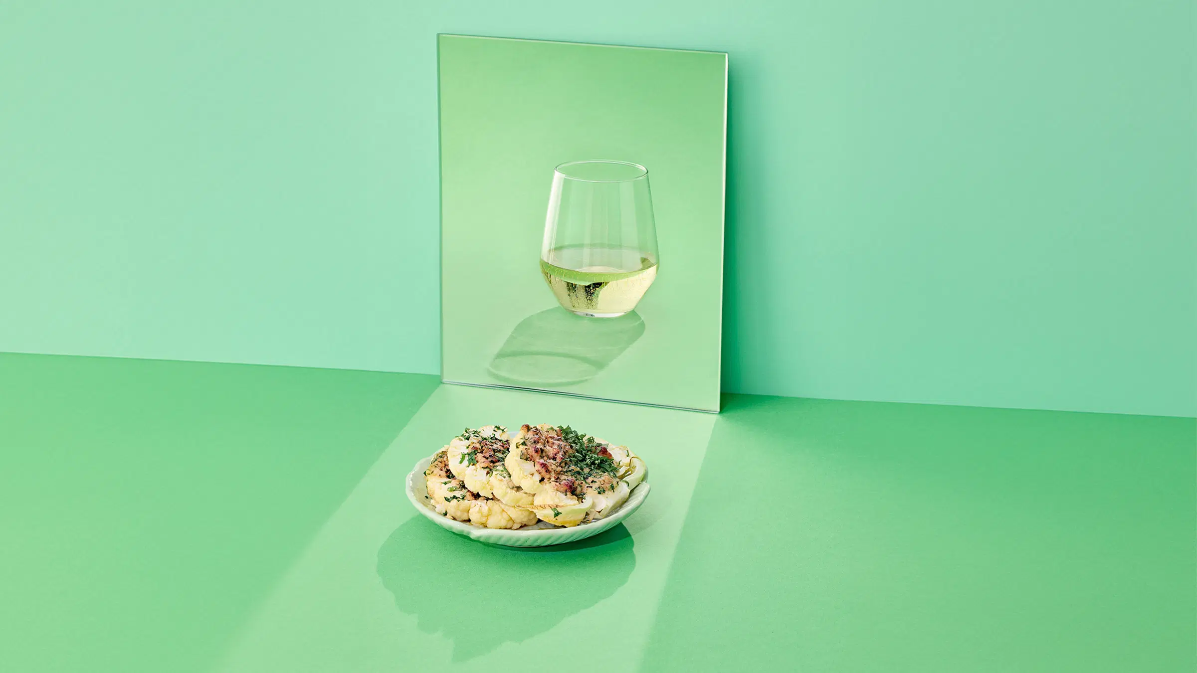 Lautanen, jossa paahdettua, parmesaanilla maustettua kukkakaalia sekä lasillinen valkoviiniä.