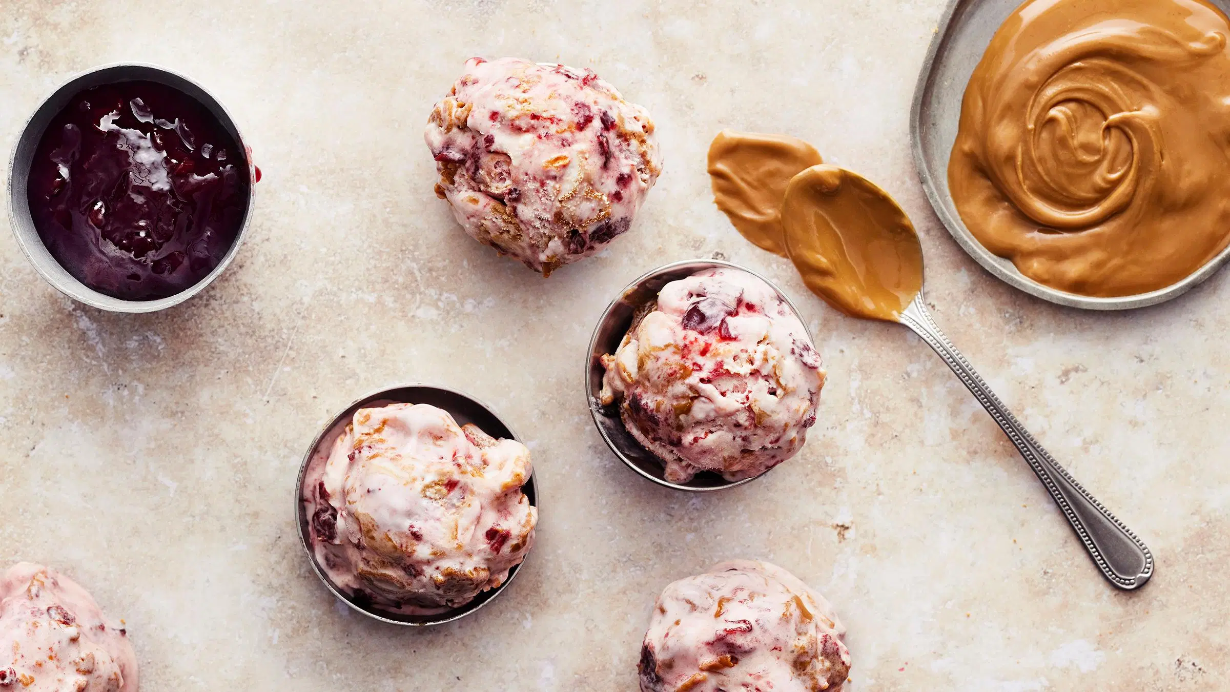 Keksilevite-kirsikkajäätelöä kolmessa kupissa sekä keksilevitettä ja kirsikkahilloa. 