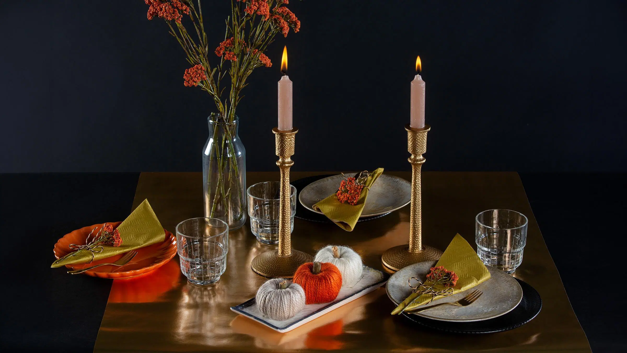 Langasta askarreltuja koristekurpitsoja syksyisen kattauksen keskellä.