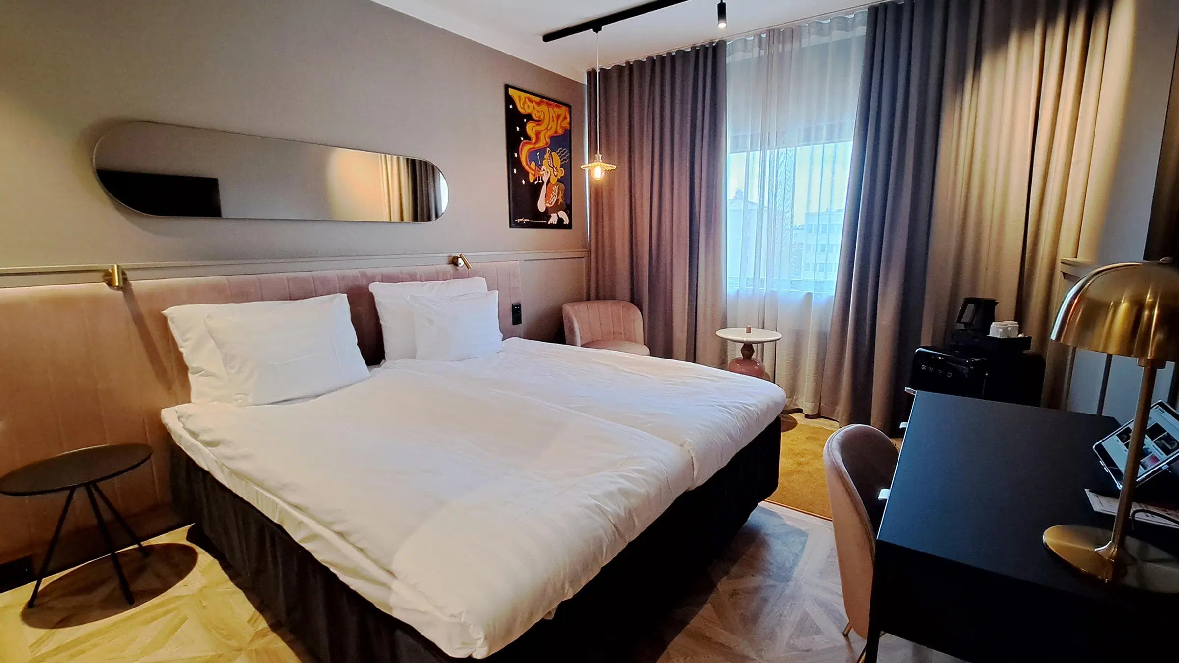 Porin Original Sokos Hotel Vaakunan huone, jossa on muhkeasti pedattu sänky, leveä peili sängyn päädyssä ja pieni työpöytä.