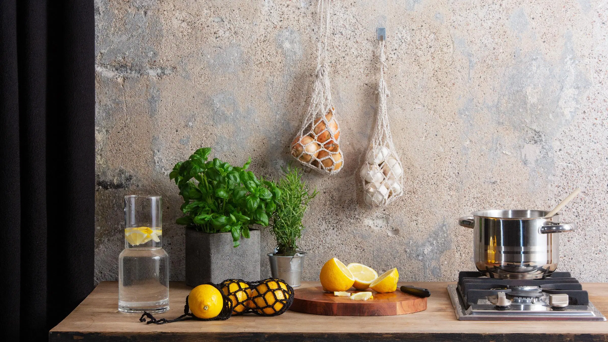 Keittiö, jonka seinällä roikkuu kaksi sipuleilla täytettyä sipulipussia.