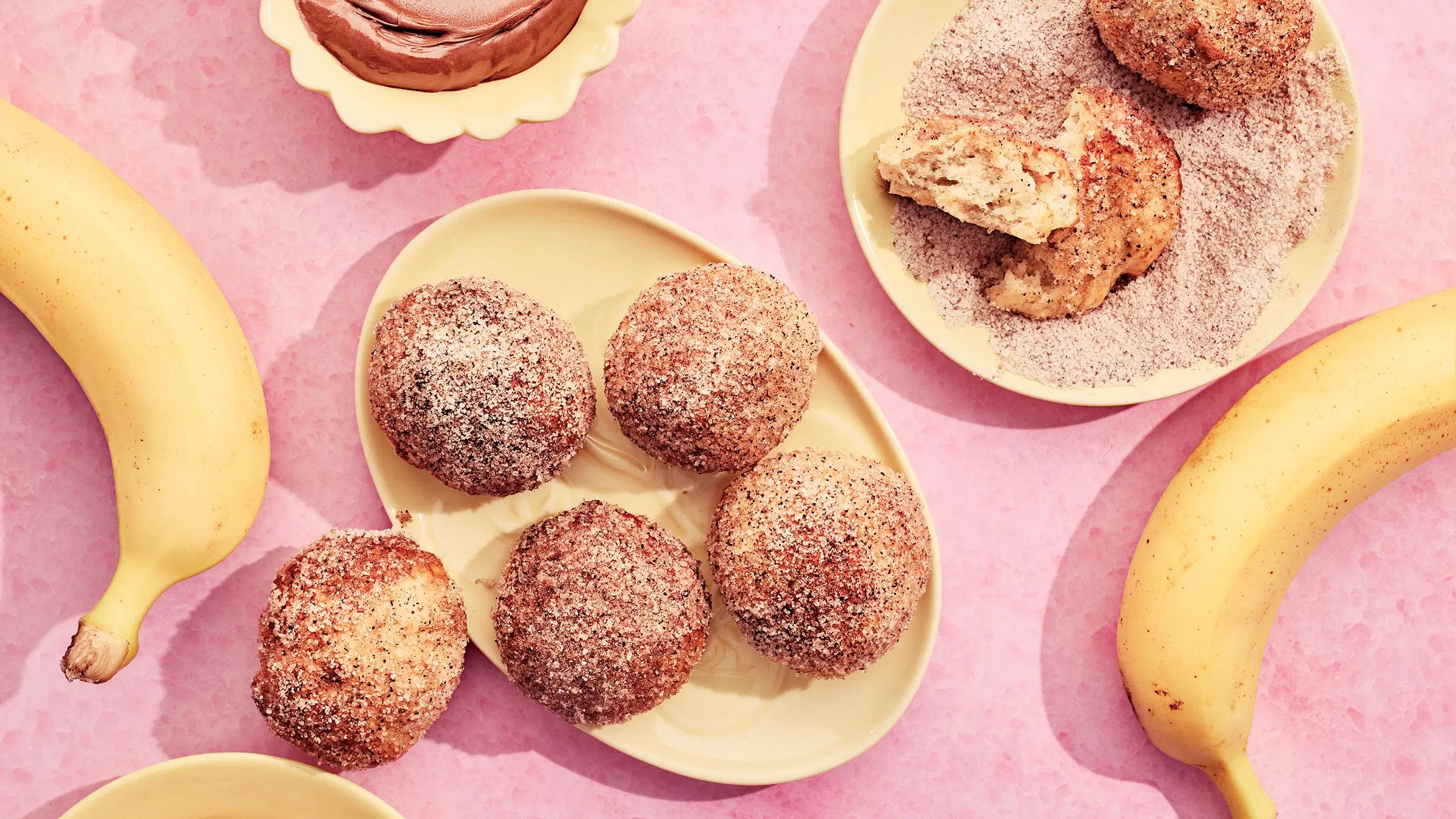 Kanelisokerissa pyöriteltyjä pieniä banaanimunkkeja lautasella.