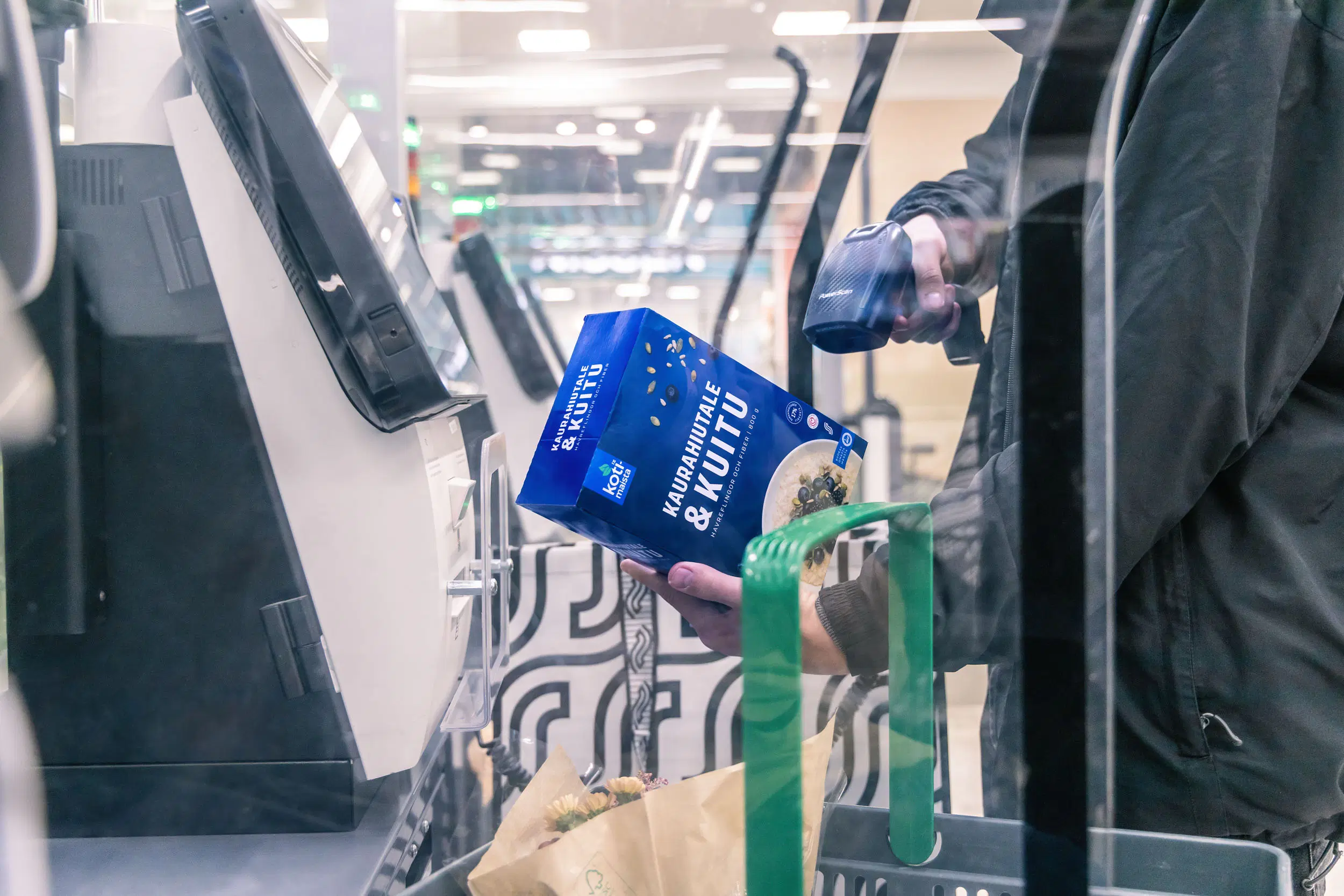 Asiakas skannaa kaurahiutalepakettia itsepalvelukassalla.