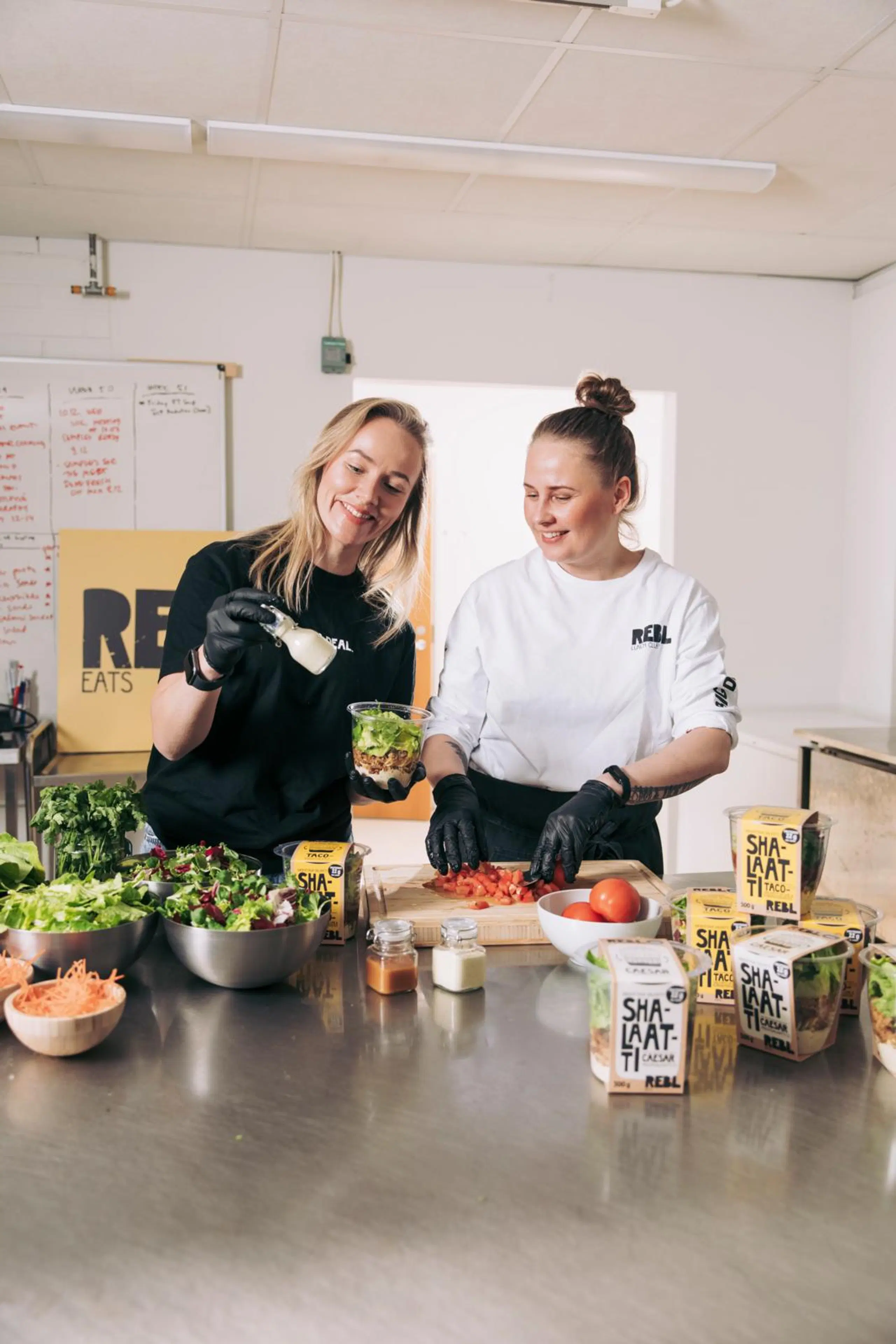 Elina Leskinen ja Tiia Longi kasaavat salaattia muovipurkkiin