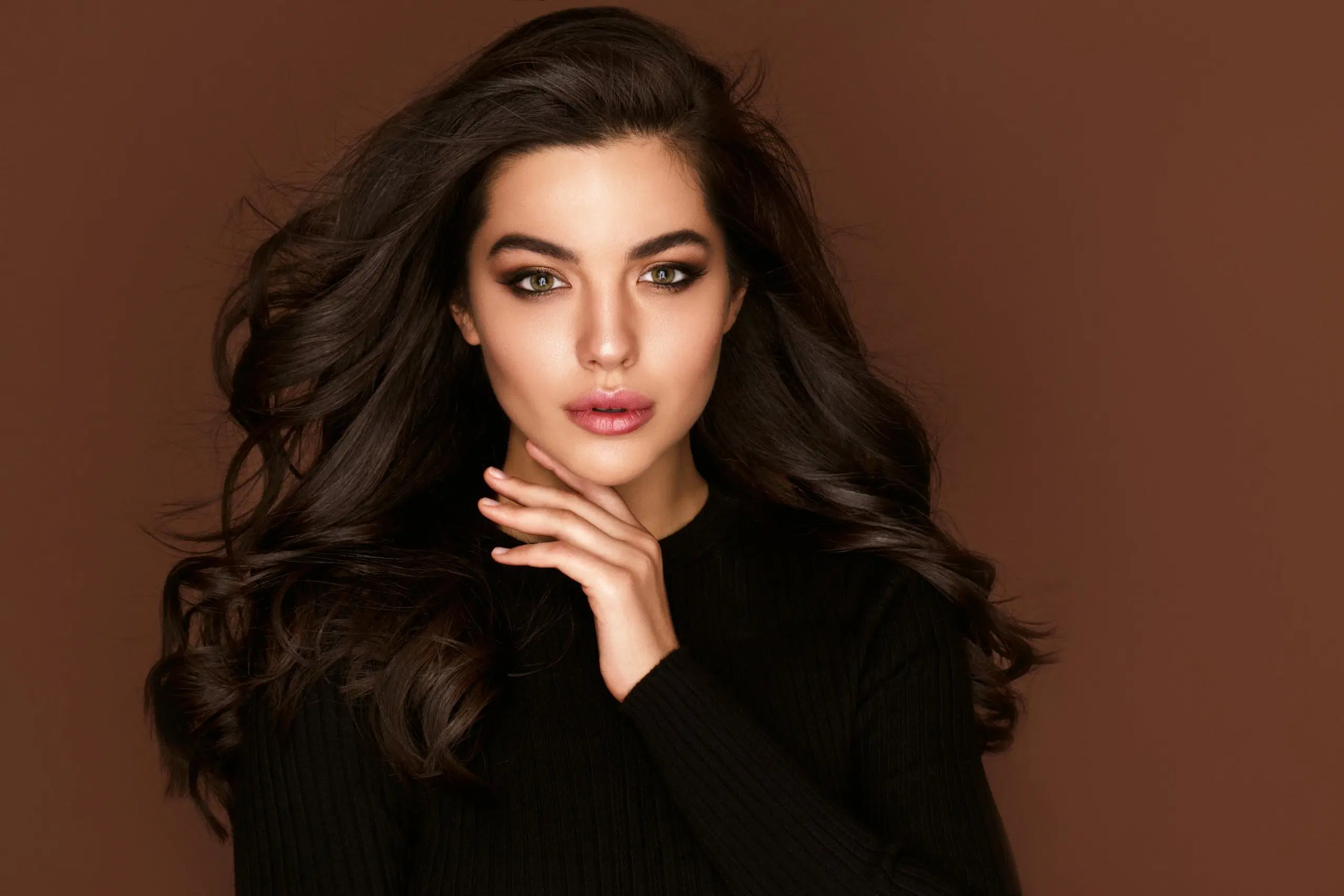 Tummahiuksinen nainen ilmavassa kampauksessa, katsoo suoraan kameraan