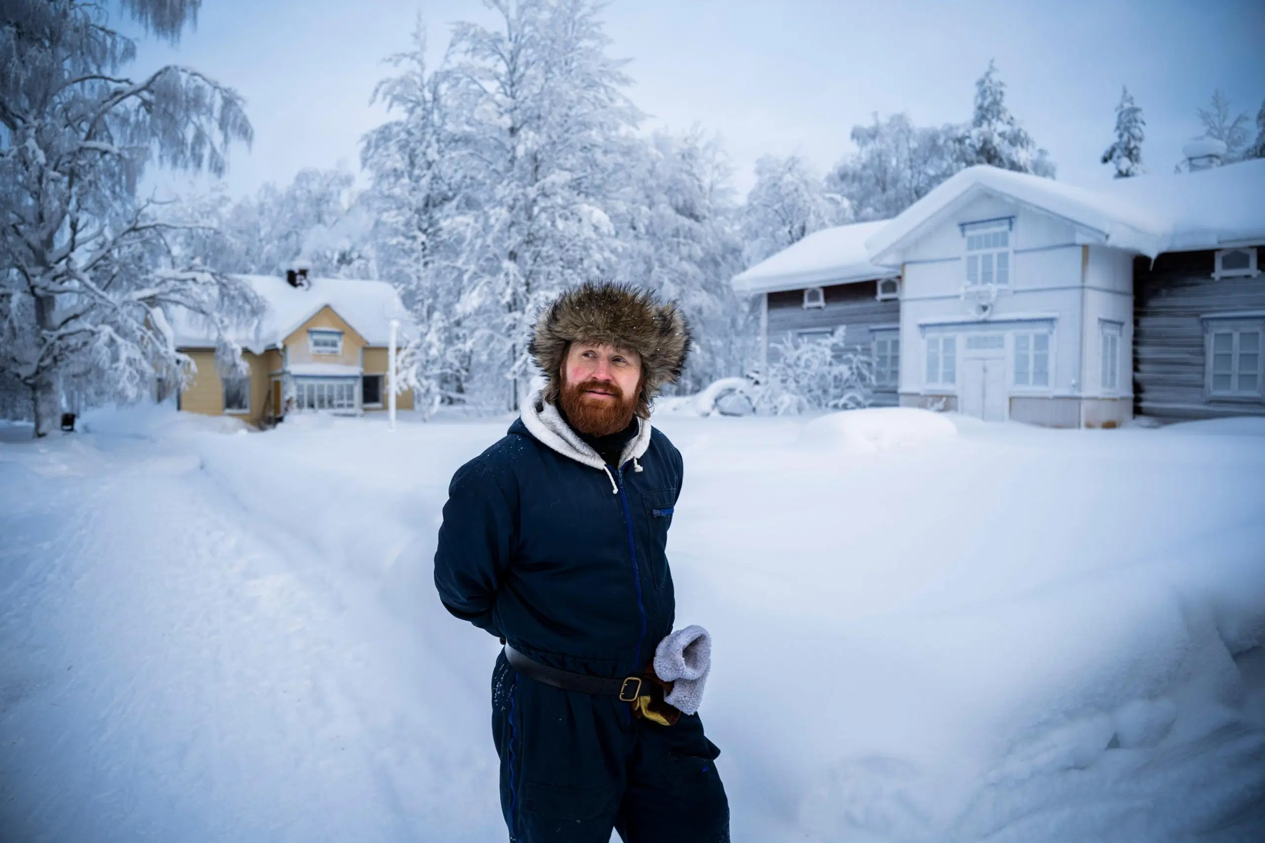 Tommi Manninen seisoo ulkona, takana kotitalo. Maisema on luminen.