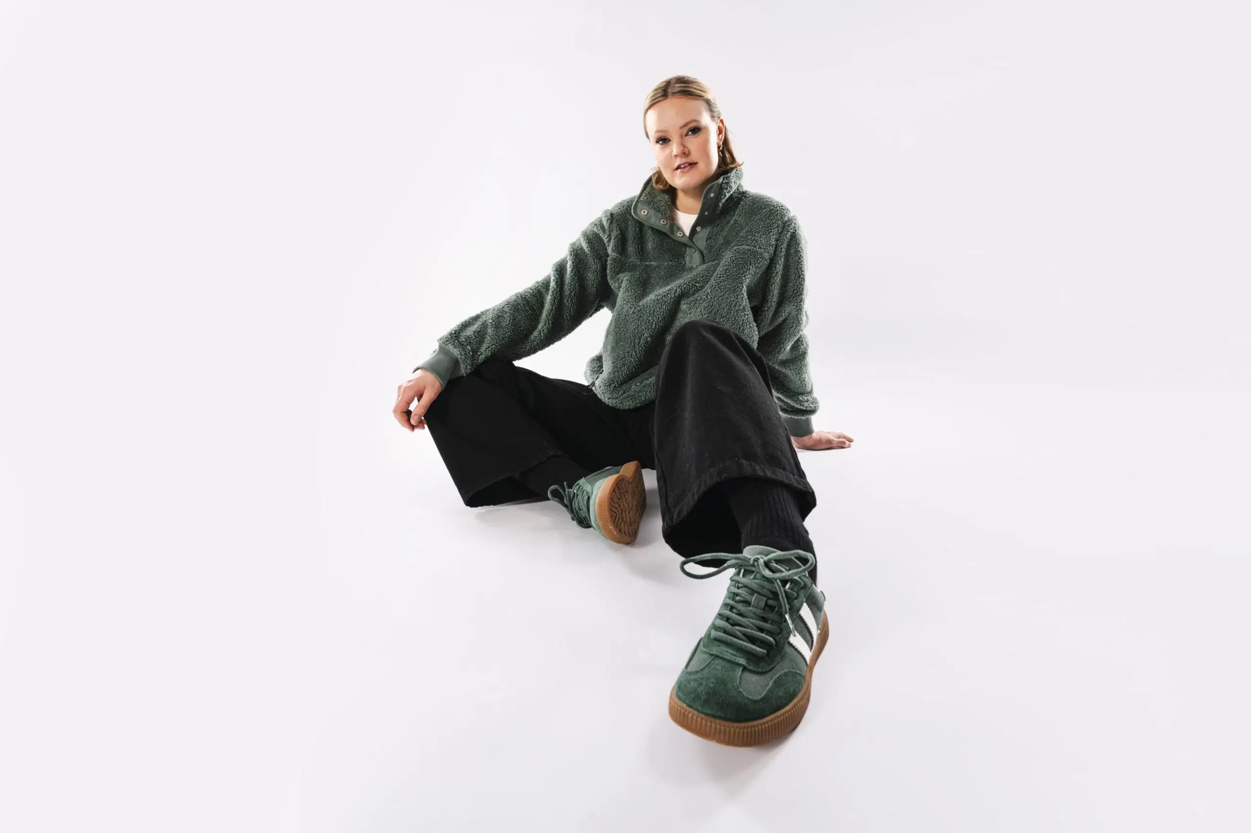 Mallilla päällä vihreä fleecepaita, mustat farkut ja vihreät tennarit.