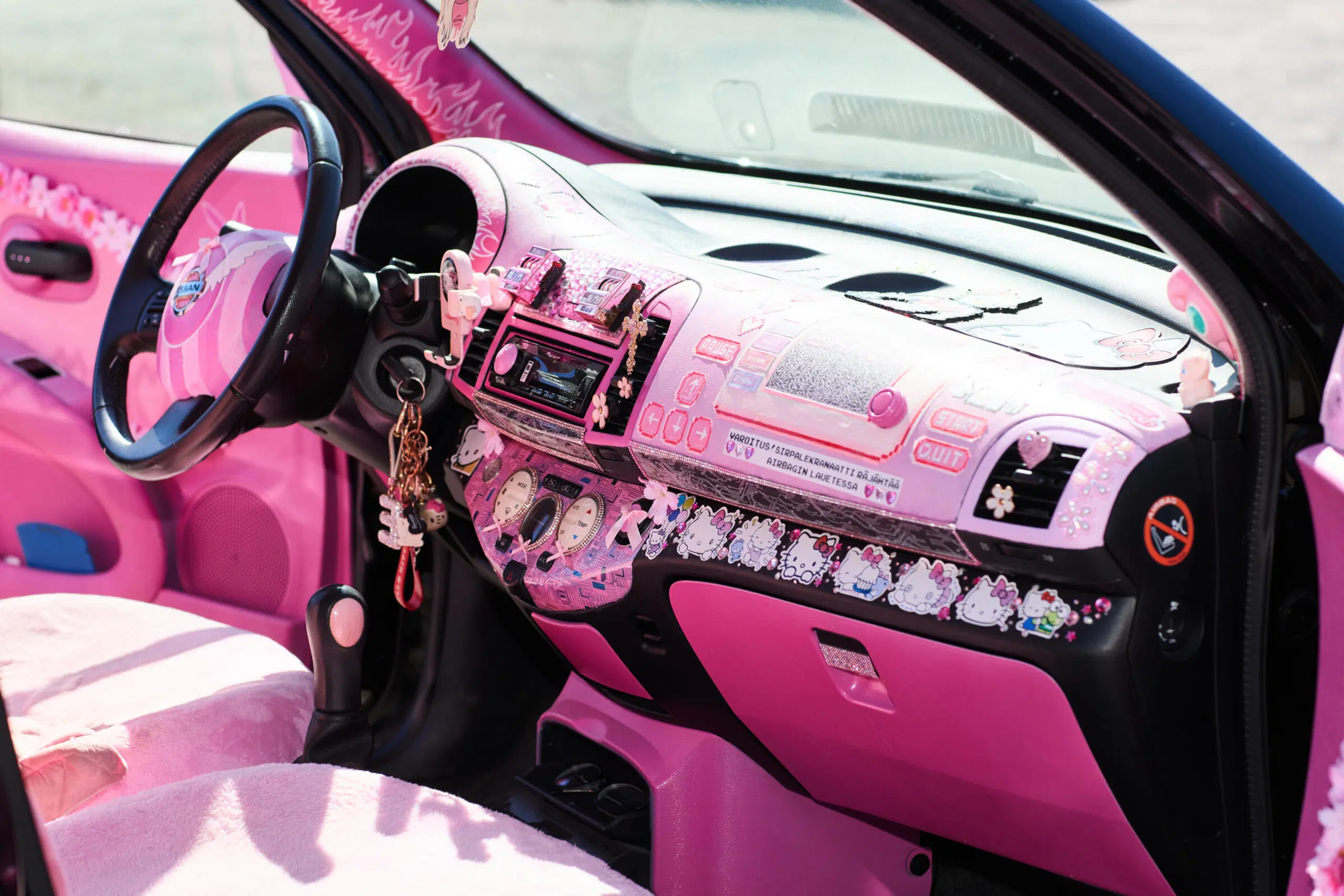 Hello Kitty -aiheiseksi tuunatun auton pinkki kojeauta on koristeltu tarroin.